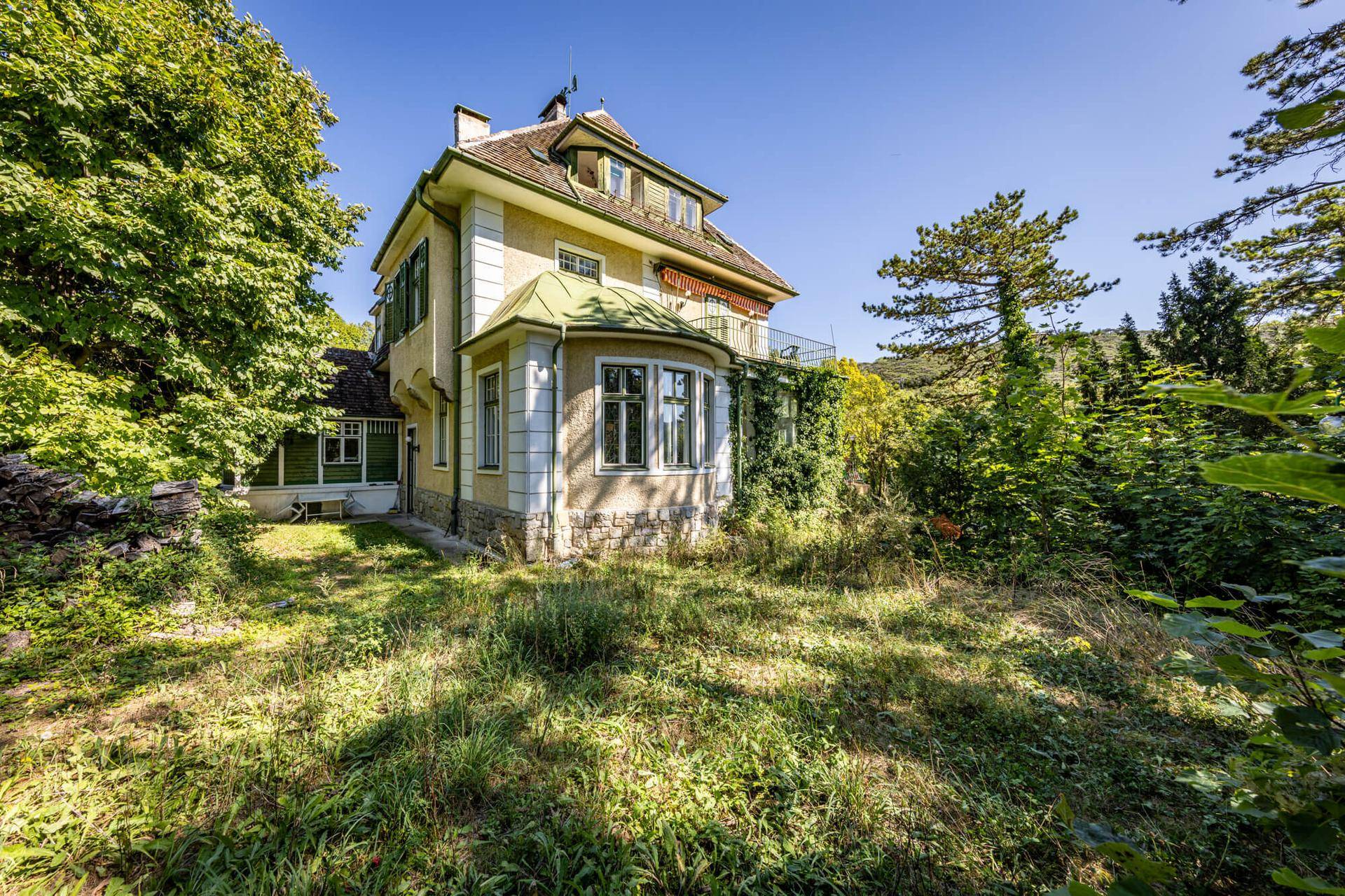 Historisches Gebäude mit traditioneller Architektur, umgeben von einem großen, naturbelassenen Garten.