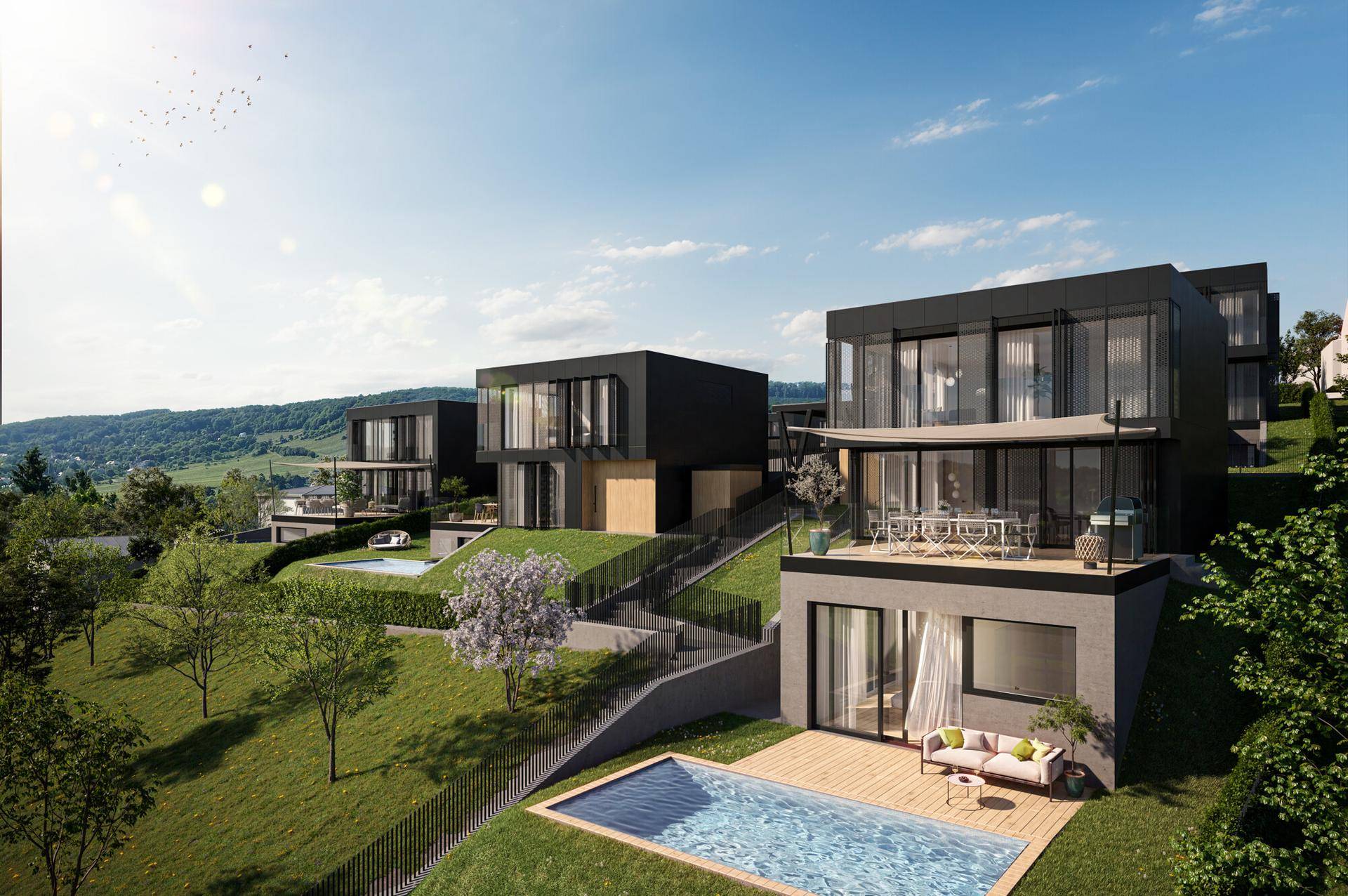 Mehrere moderne Villen auf einem grünen Hang mit Pools und Blick auf die umliegende Landschaft.