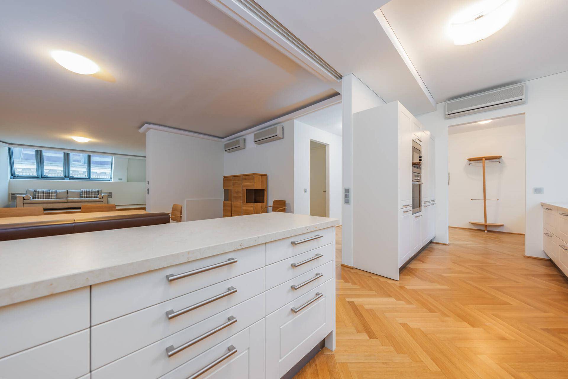 Moderne Küche mit weißen Schränken, offenem Essbereich und Kaminofen im Hintergrund.