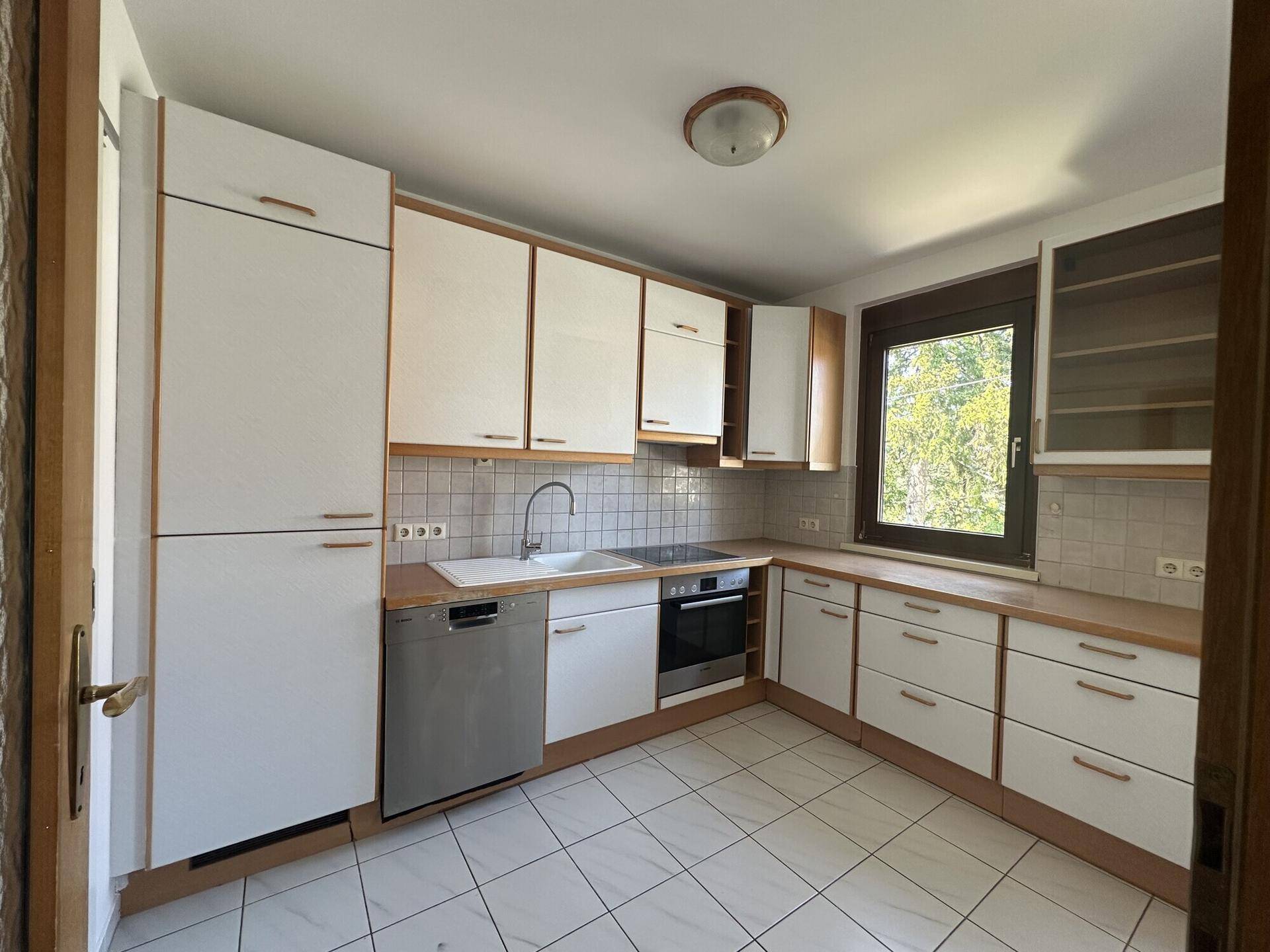 Funktionale Einbauküche mit weißen Schränken, Holztheke und integriertem Geschirrspüler.