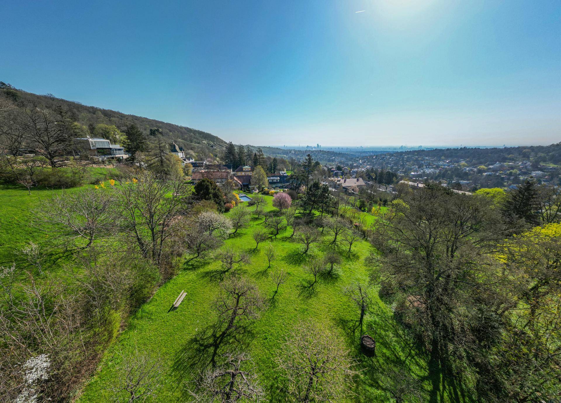 Weitläufiger Garten mit Obstbäumen und Blick auf die umliegende Landschaft und die Stadt in der Ferne.