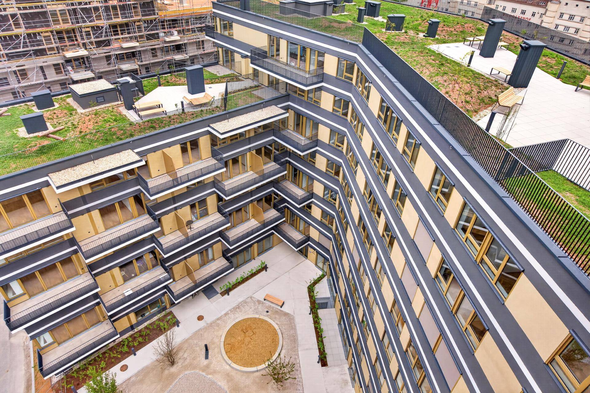Vogelperspektive eines modernen Wohnkomplexes mit begrüntem Dach und Innenhof.
