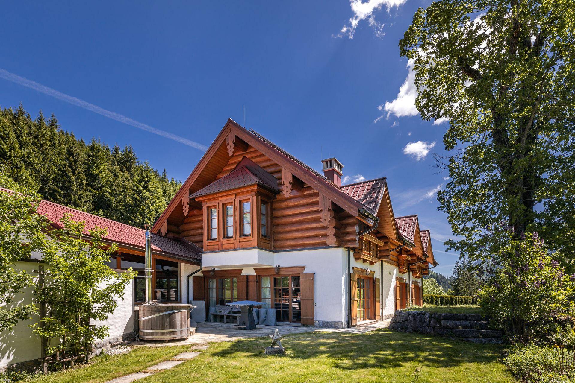 Idyllischer Gartenbereich mit Holz-Whirlpool, Terrasse und Blick auf den Wald.
