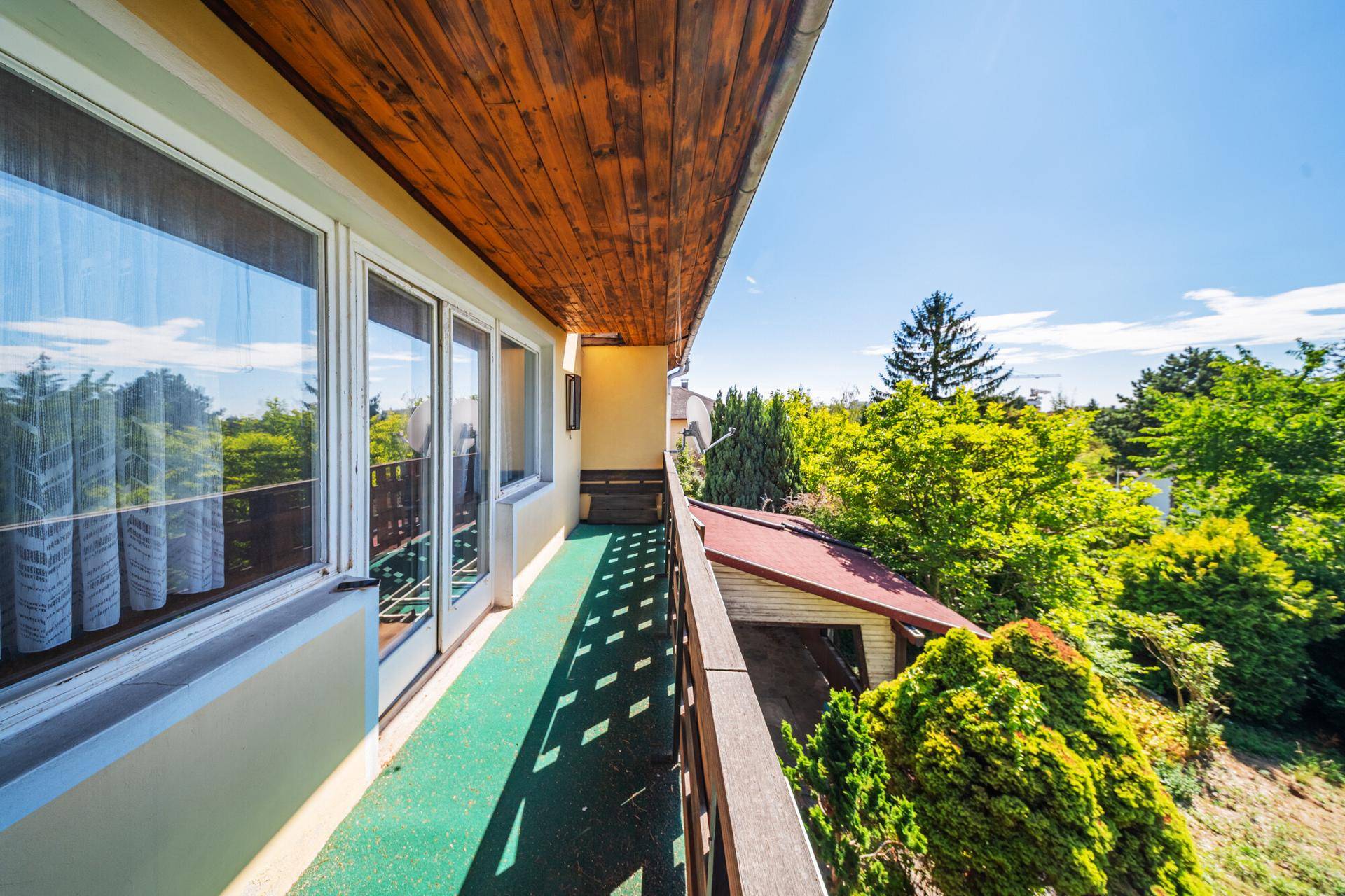 Langer Balkon mit Holzdecke und weitem Blick ins Grüne, ideal zum Entspannen im Freien.