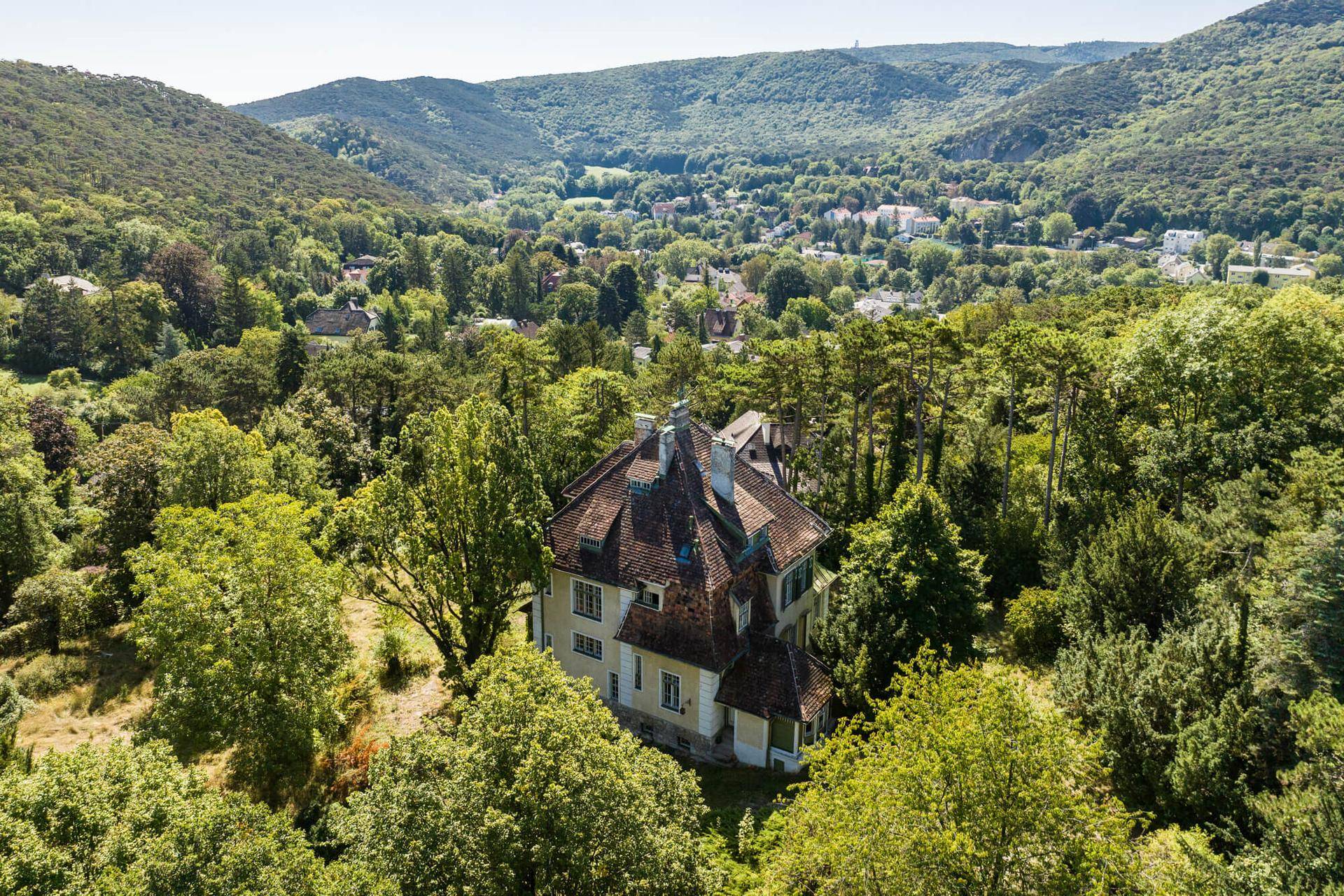 Weitläufige Luftaufnahme der Villa, umgeben von einer malerischen Wald- und Hügellandschaft.