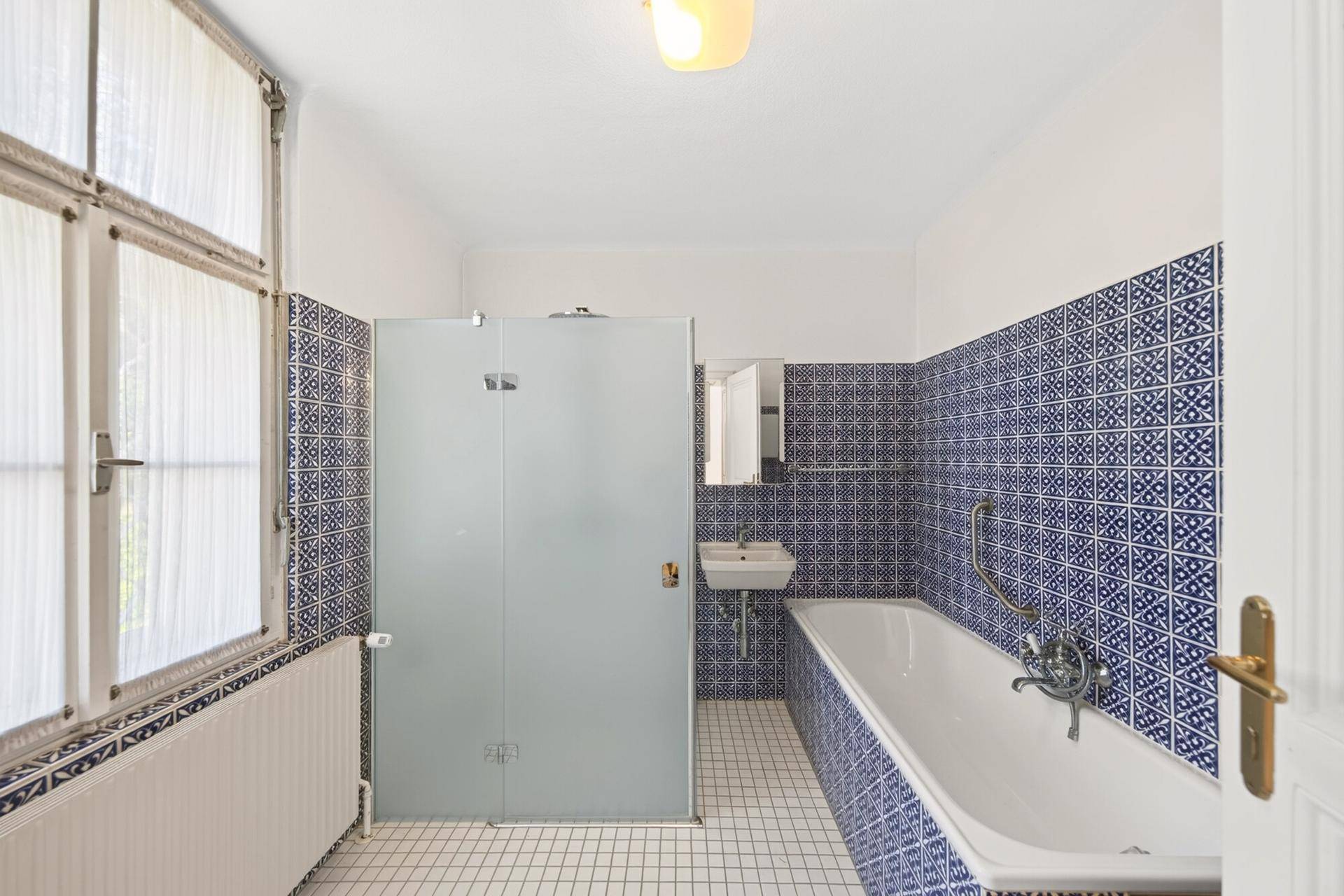 Badezimmer mit blauen Fliesen, Badewanne und separater Duschkabine.
