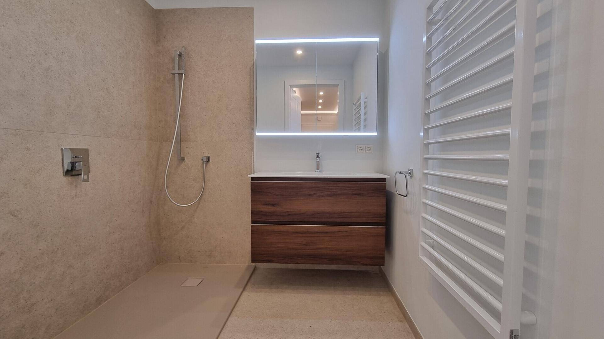 Modernes Badezimmer mit begehbarer Dusche, schwebendem Waschtisch und beheiztem Handtuchhalter.
