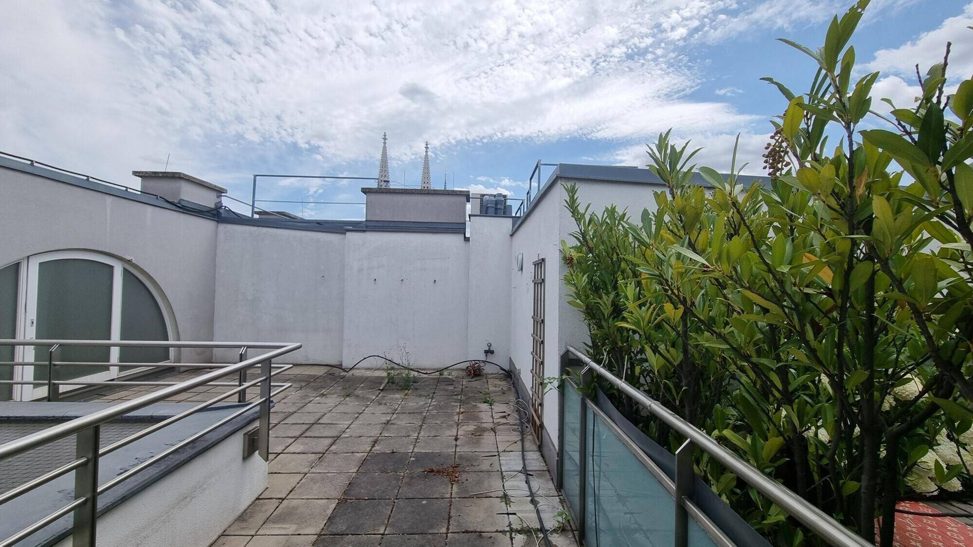 Dachterrasse mit Blick auf die Umgebung, umgeben von niedrigen Mauern und Pflanzen.