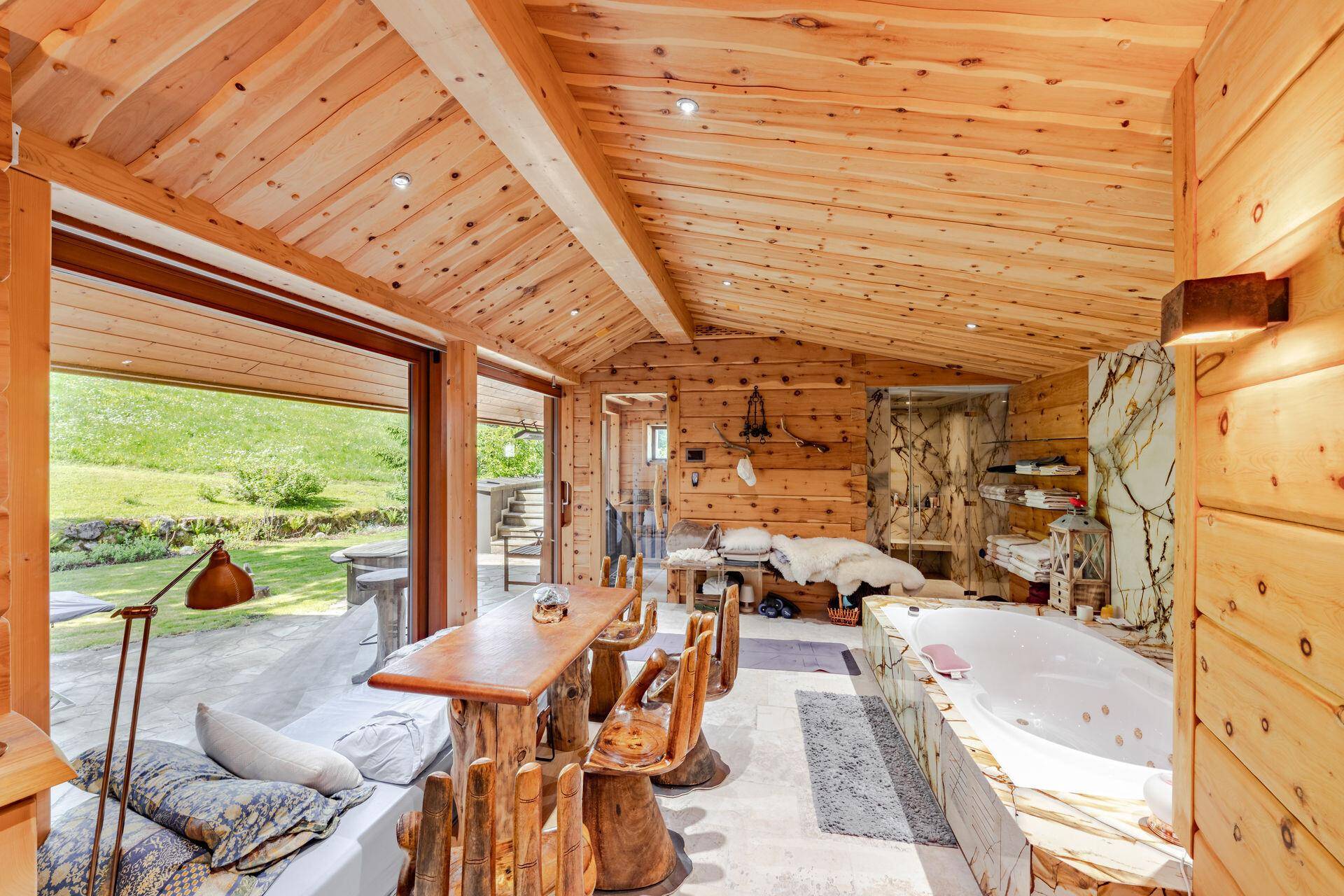 Gemütlicher Wellnessbereich mit Whirlpool, Holzeinrichtung und Zugang zur grünen Natur.