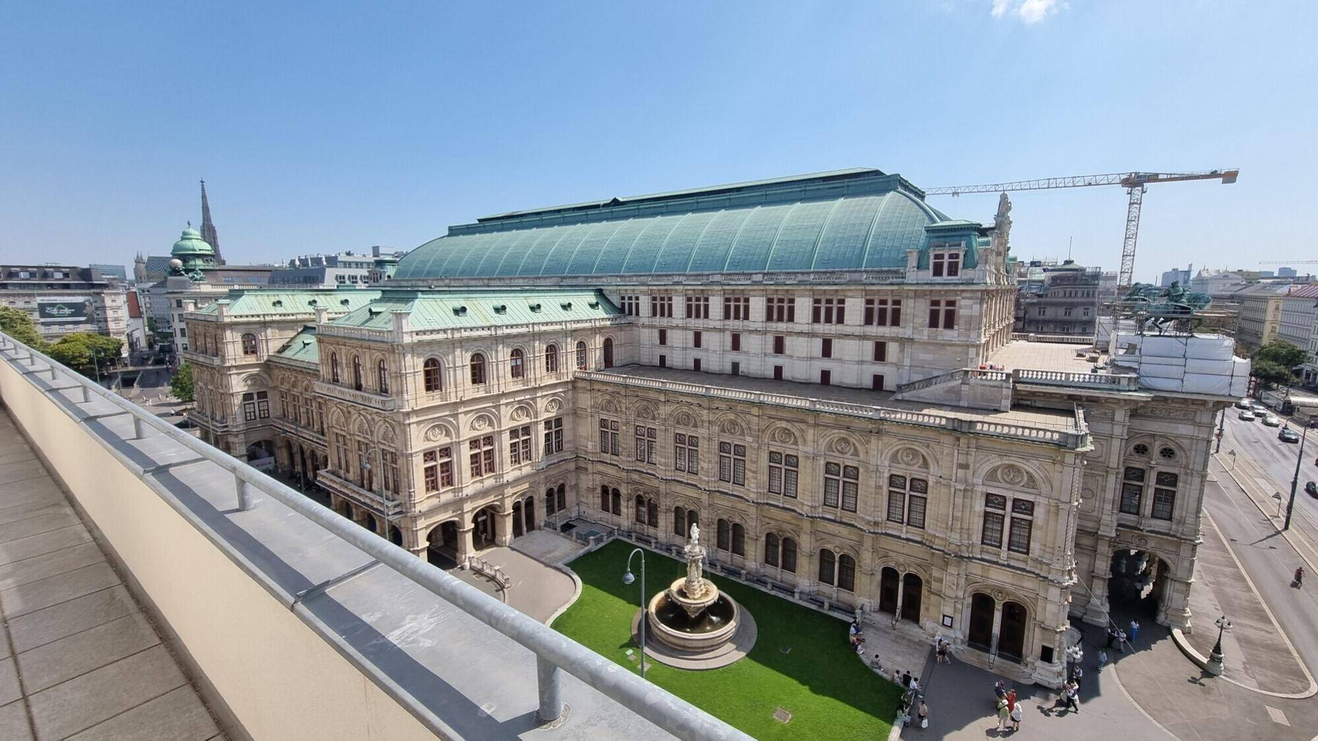 Panoramablick auf ein historisches Gebäude mit grüner Kuppel und Stadtansicht.