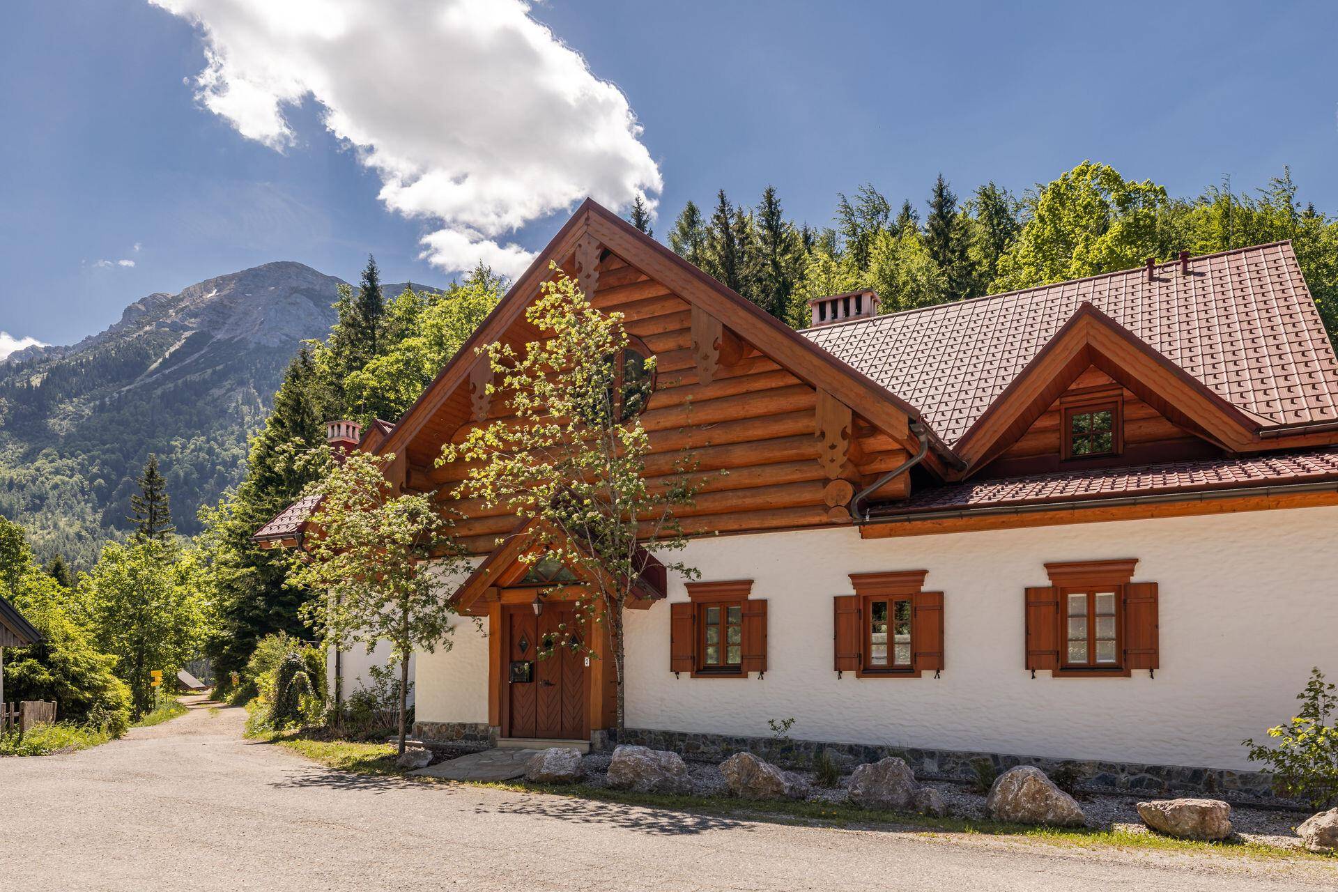Traditionelles Chalet-Haus mit Holzelementen, weißer Fassade und Bergblick.