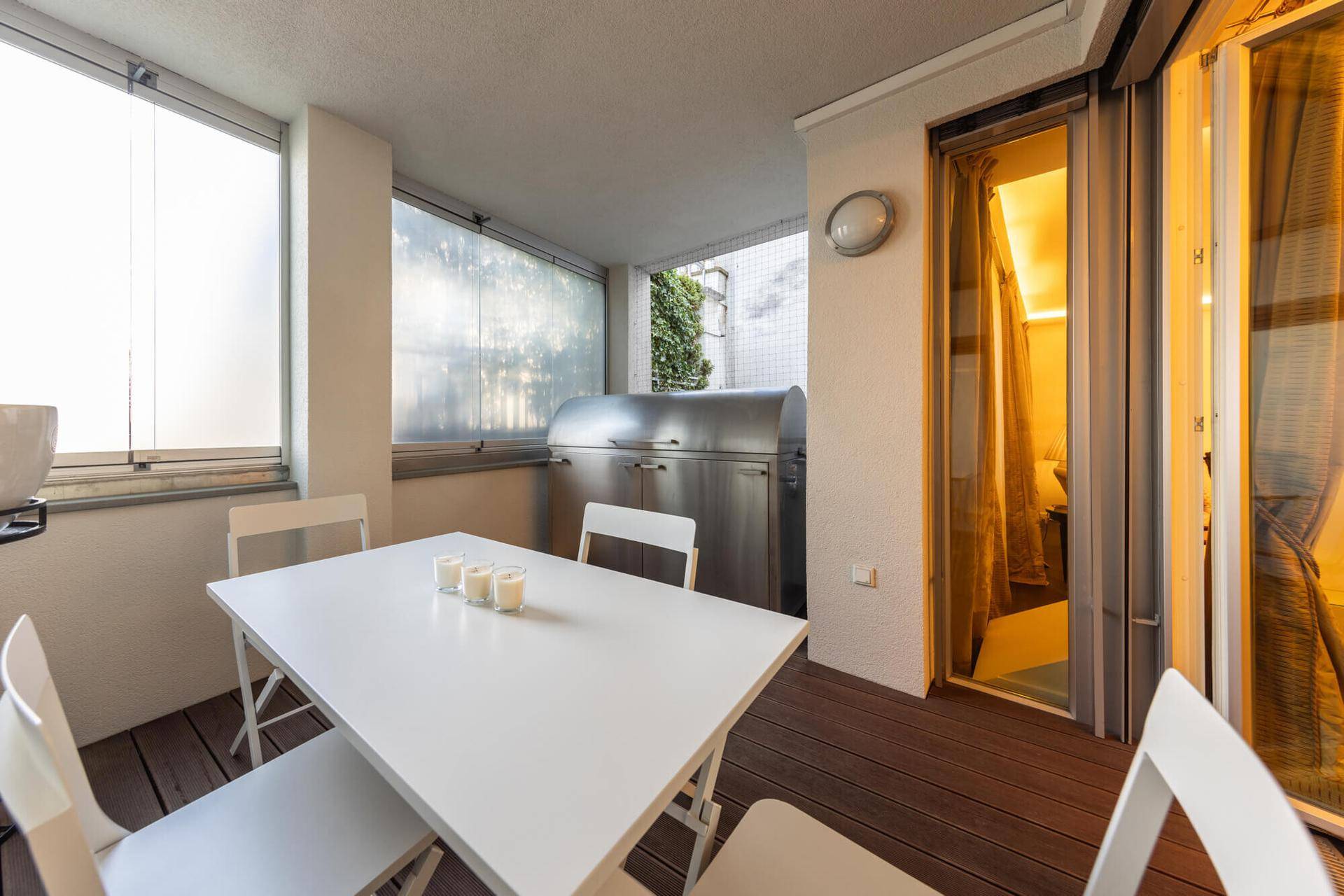 Überdachte Terrasse mit Holzboden, Esstisch und integriertem Grillbereich.