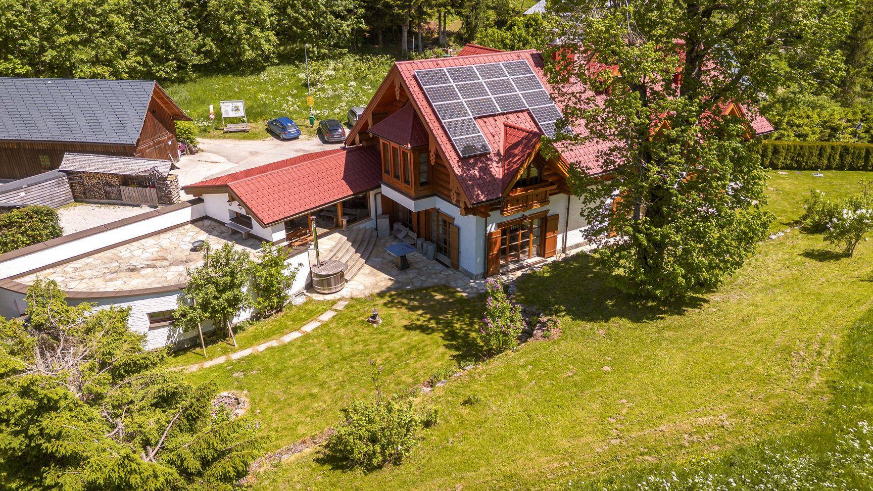 Vogelperspektive des Chalet-Hauses mit Photovoltaikanlage, Garten und umliegender Natur.