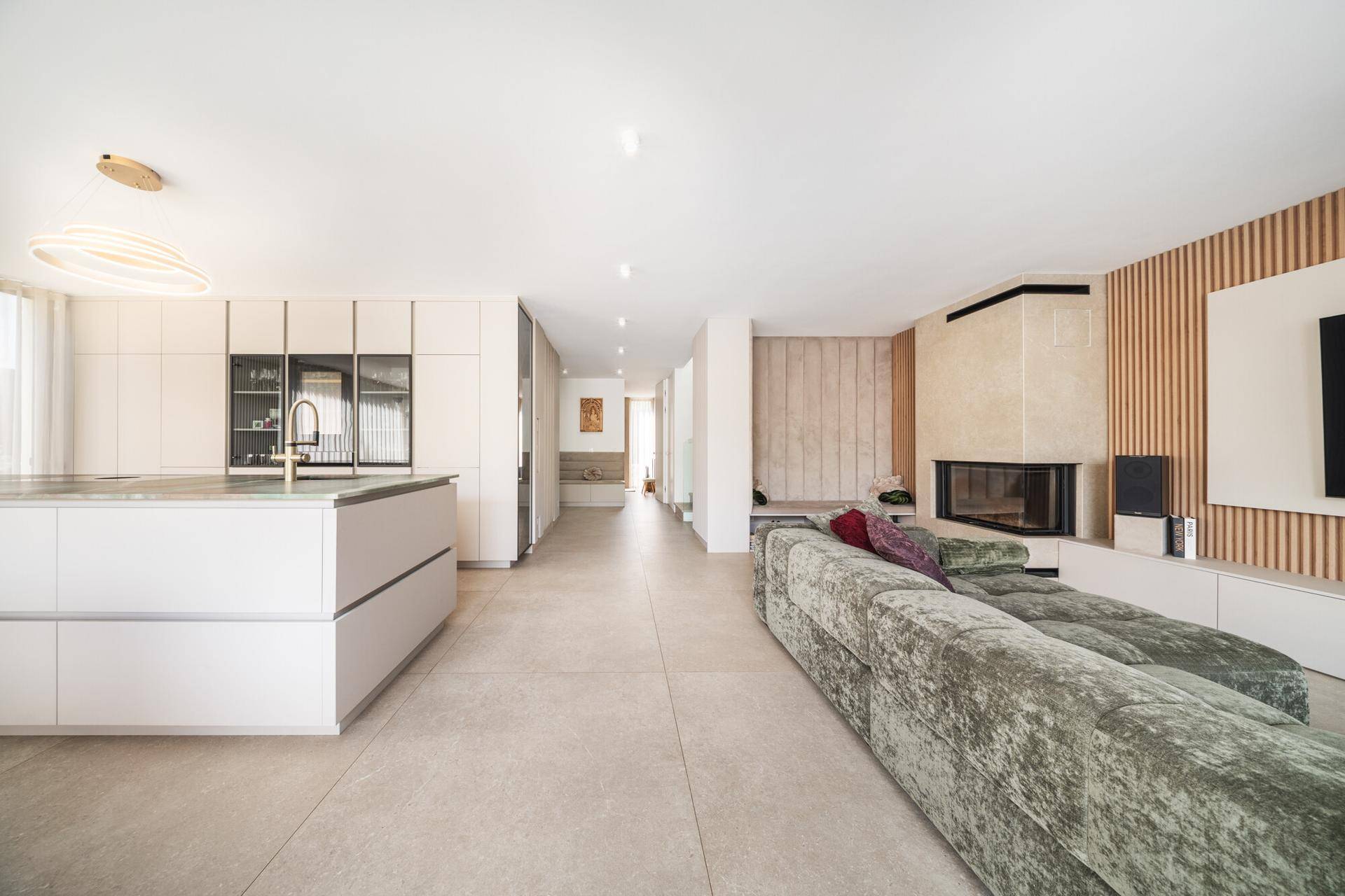Geräumiger Wohn-Essbereich mit integrierter Küche, Kamin und großem Sofa, hell und modern gestaltet.