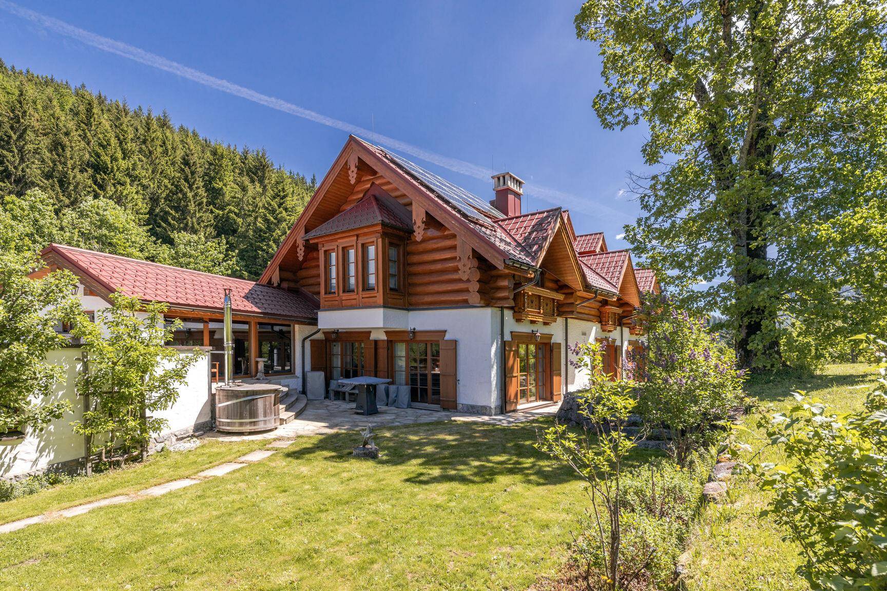 Großzügiger Garten mit Chalet-Haus, Holz-Whirlpool und Photovoltaikanlage auf dem Dach.
