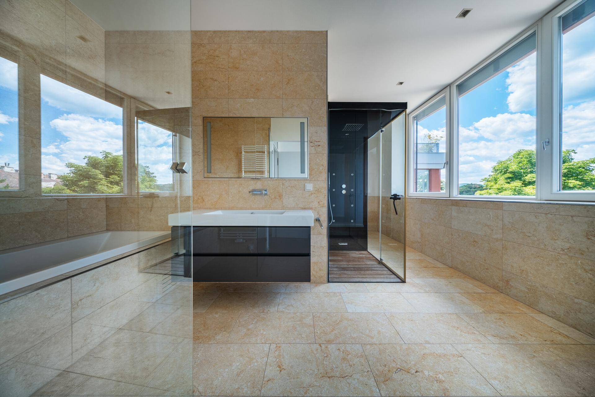 Luxuriöses Badezimmer mit beigen Fliesen, schwebendem Waschtisch, Badewanne und einer begehbaren Dusche.