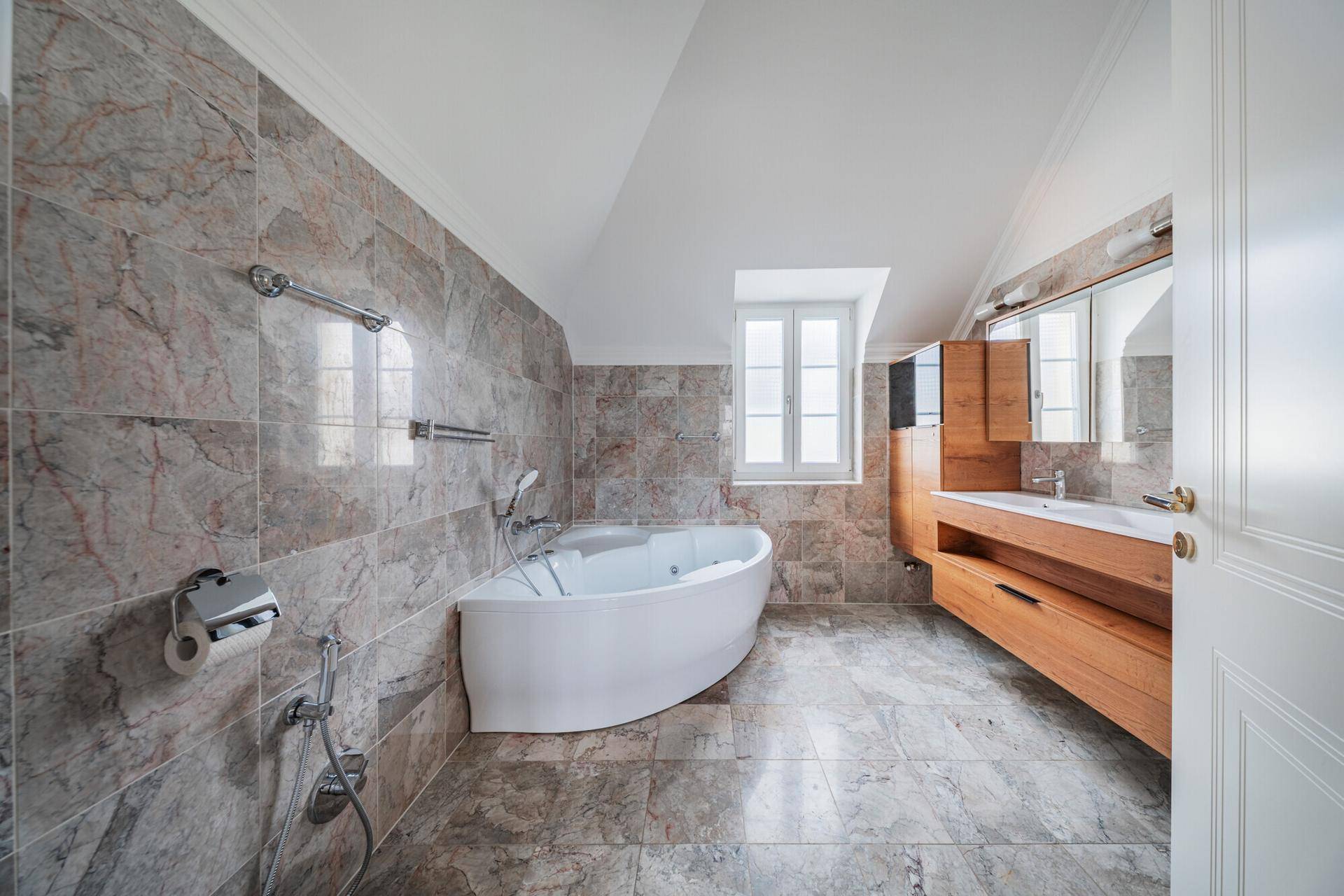Elegantes Badezimmer mit Marmorfliesen, freistehender Badewanne und Holzwaschtisch.