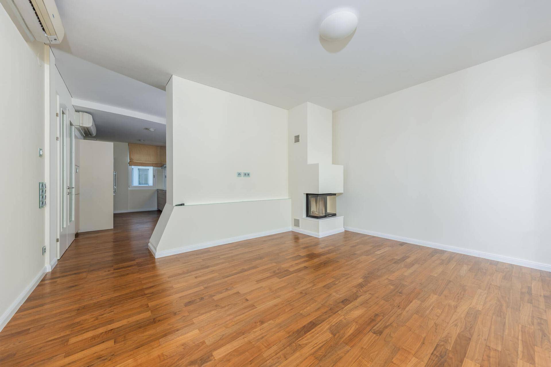 Geräumiges Wohnzimmer mit Holzboden und integriertem Kamin, bereit zur individuellen Gestaltung.
