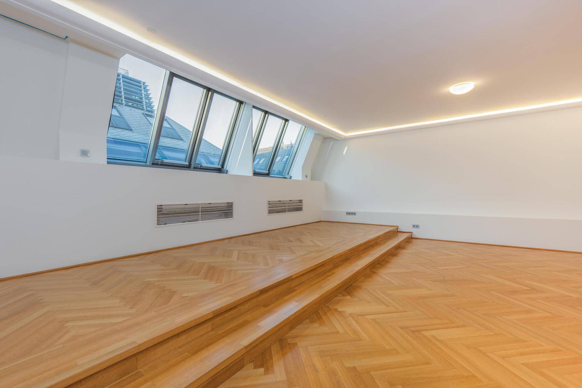 Lichtdurchfluteter Wohnbereich mit erhöhtem Podest und schrägen Dachfenstern.