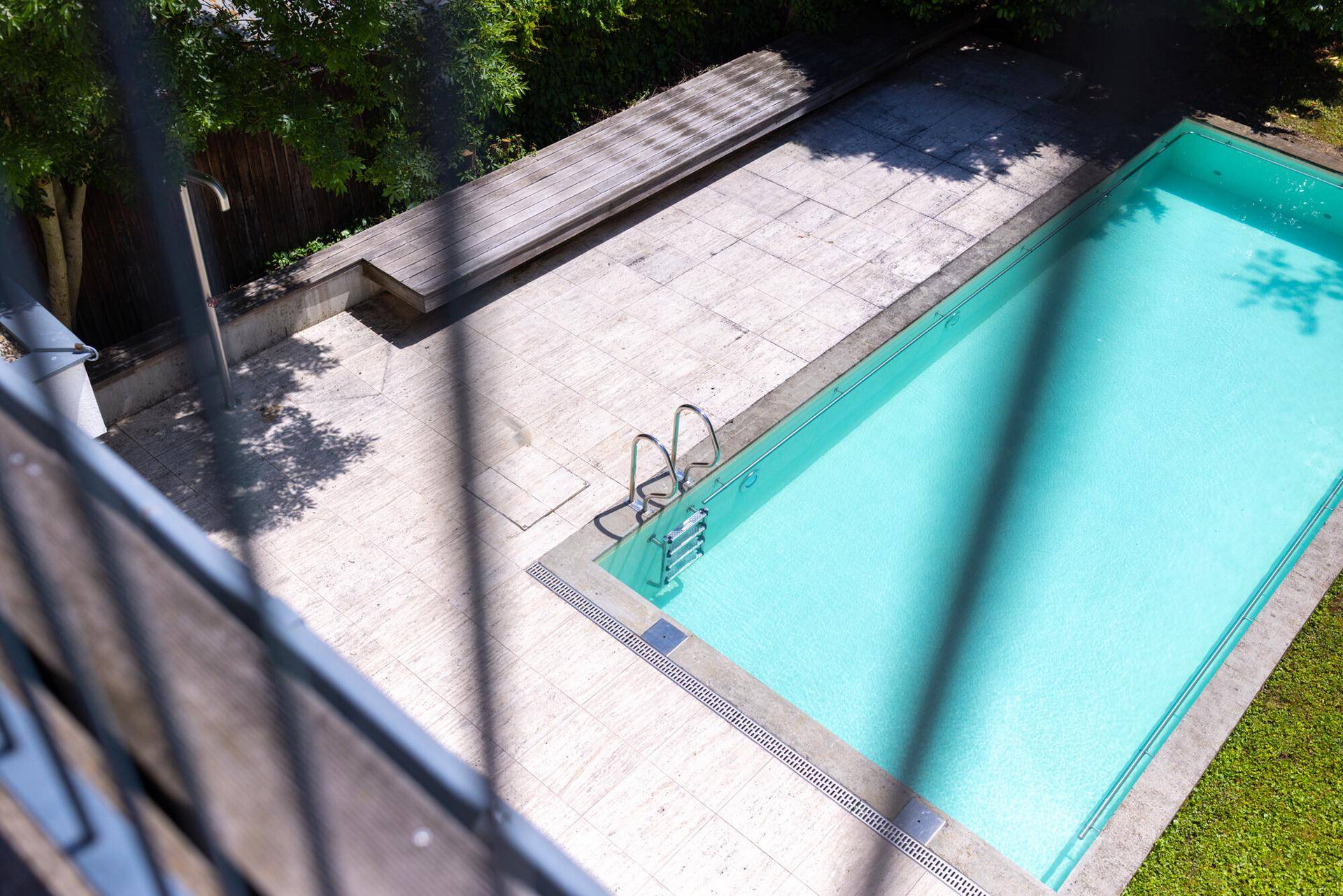 Ansicht des Pools von oben mit umliegender Terrasse und Holzdeck.