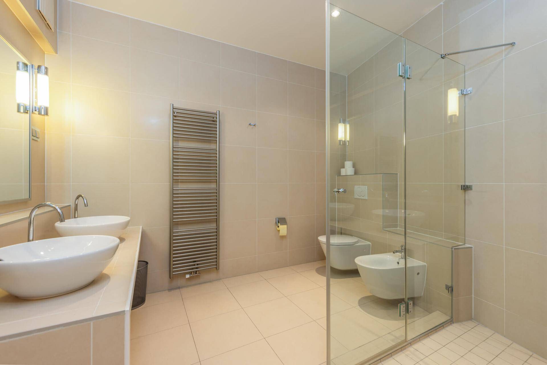 Modernes Badezimmer mit doppelten Waschbecken, begehbarer Dusche und beheiztem Handtuchhalter.