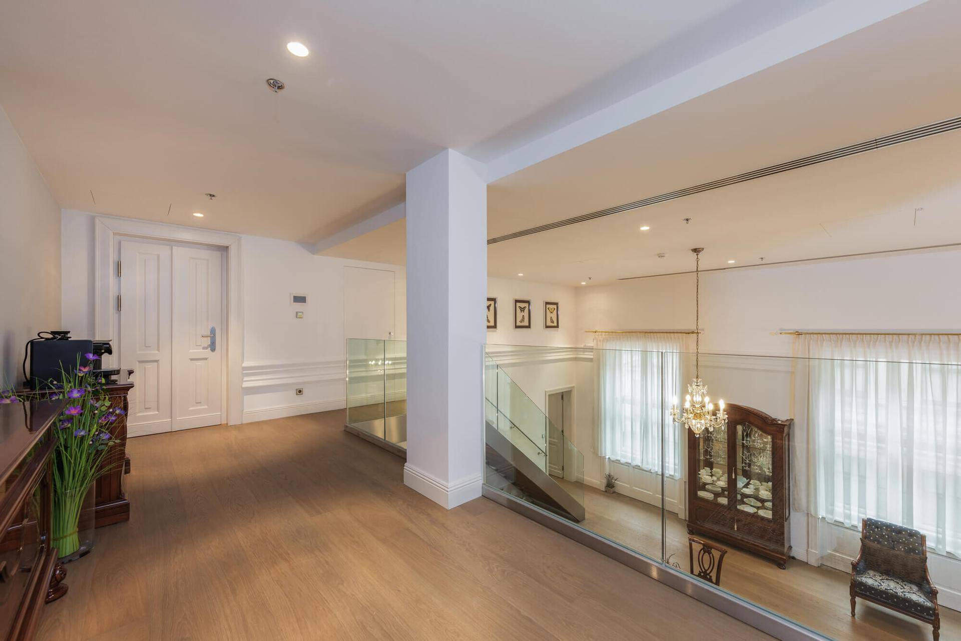 Heller Galeriebereich mit Glasgeländer und Blick auf den unteren Wohnbereich.