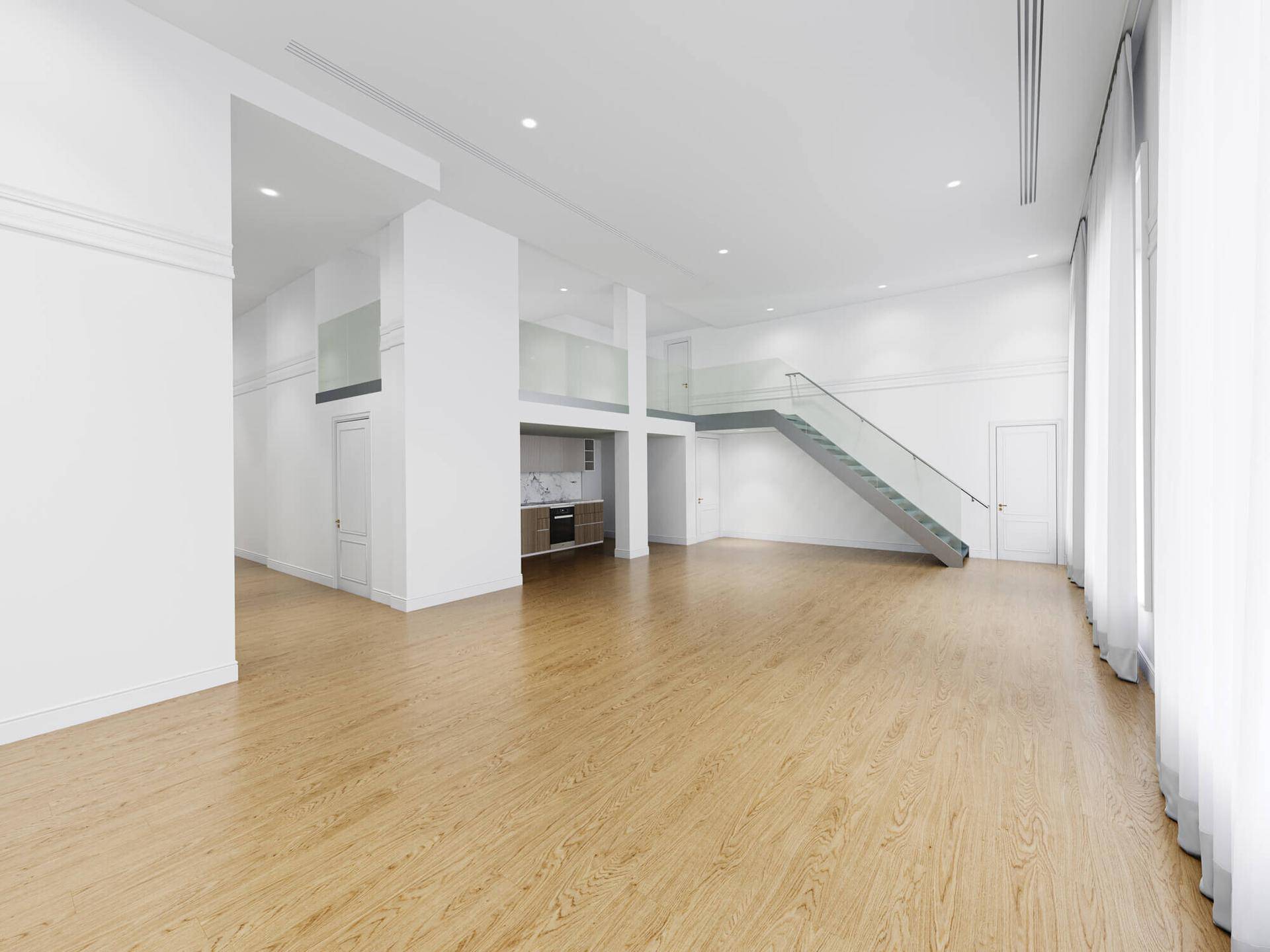 Großer, leerer Wohnbereich mit hohen Decken, Parkettboden und moderner Treppe.