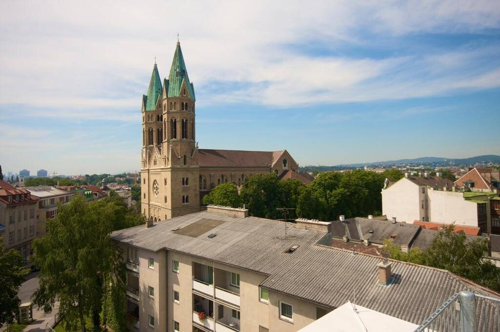 Panoramablick über die Stadt mit einer markanten Kirche, Wohngebäuden und einem weiten Himmel.