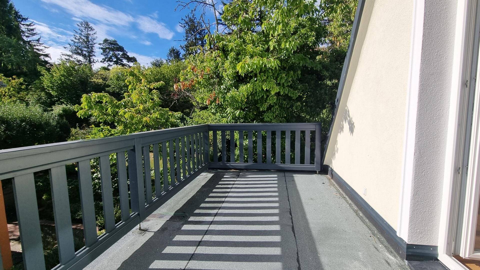 Geräumiger Balkon mit grauen Geländern und Blick ins Grüne.