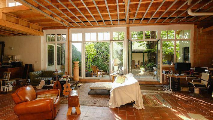 Geräumiges Wohnzimmer mit großen Fenstern, die einen schönen Blick in den Garten bieten. Die Holzdecke und der Terrakottaboden verleihen dem Raum einen warmen Charakter.
