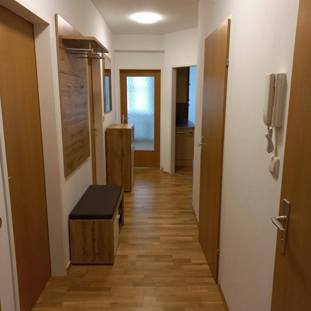 Heller Flur mit Holzfußboden, Garderobe und mehreren Türen, die zu anderen Räumen führen.