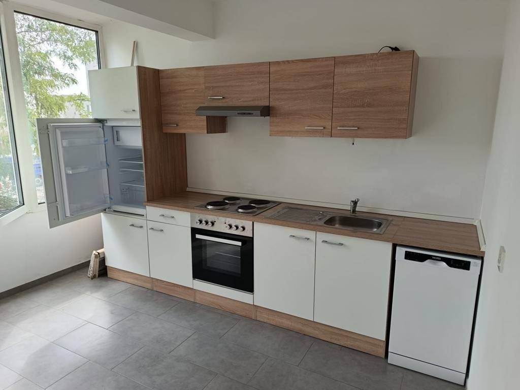 Kleine Einbauküche mit weißen und holzfarbenen Fronten, ausgestattet mit Kühlschrank und Geschirrspüler.