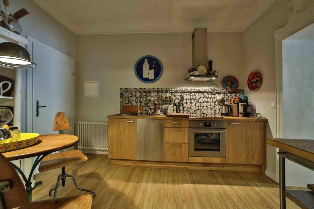 Funktionale Küche mit Holzelementen, Fliesenrückwand und Essbereich.