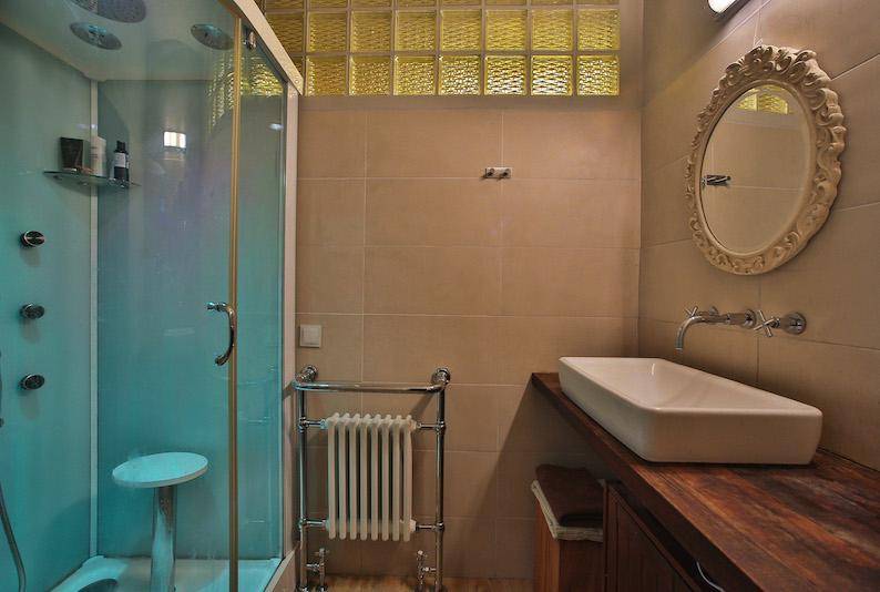 Modernes Badezimmer mit begehbarer Dusche, Holzwaschtisch und beheiztem Handtuchhalter.