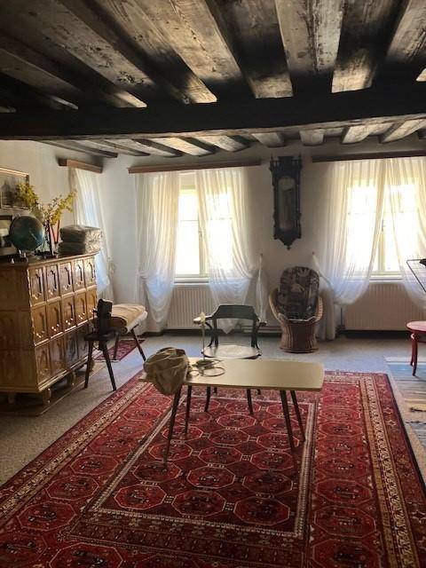 Gemütliches Wohnzimmer mit sichtbaren Holzbalken an der Decke und traditionellen Möbeln.