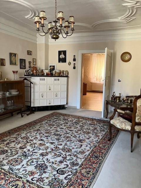 Elegantes Wohnzimmer mit Stuckdecke, einem traditionellen Kachelofen und einem großen Orientteppich.