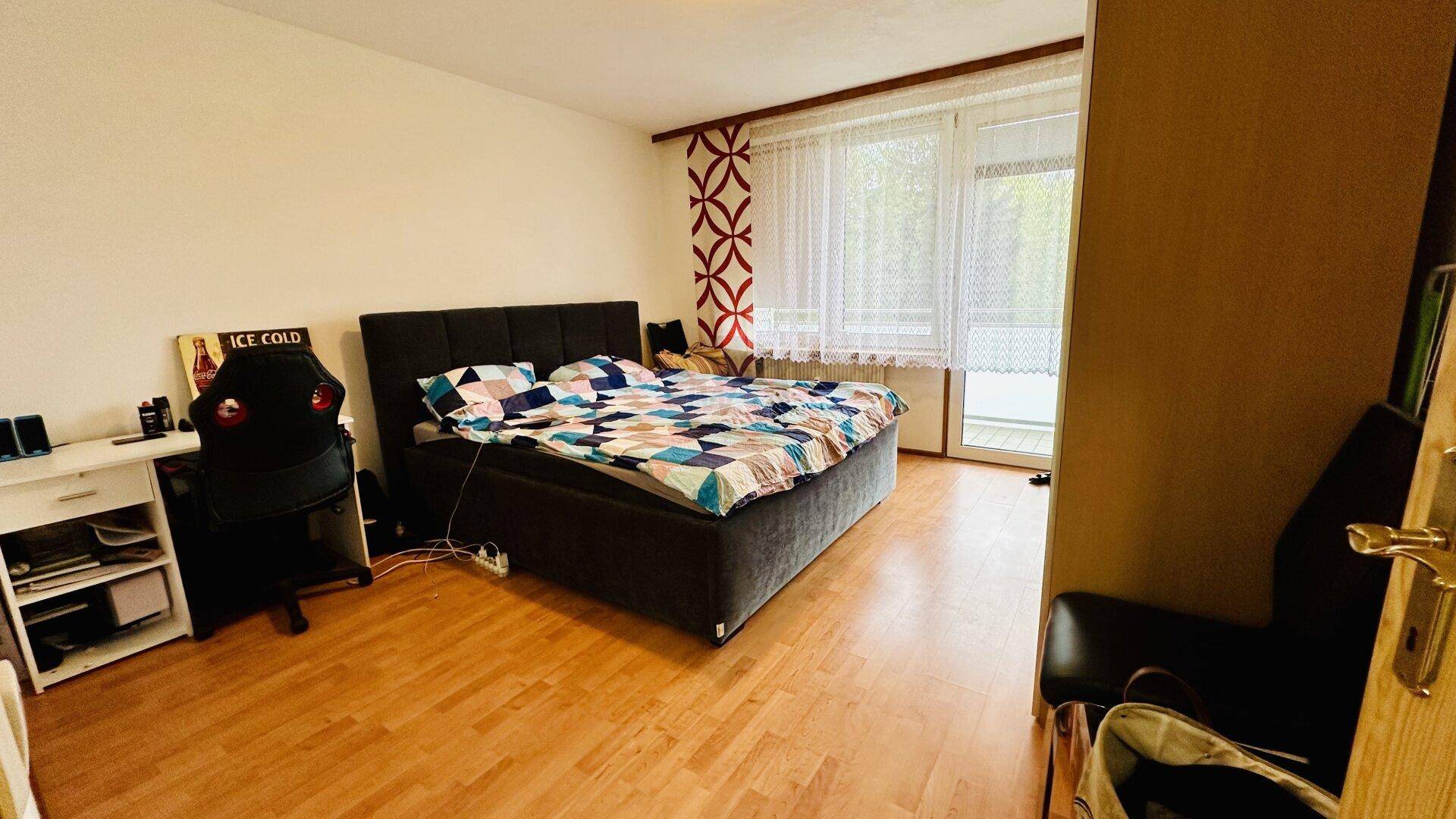 Geräumiges Schlafzimmer mit Doppelbett, Schreibtisch und Holzboden, gut beleuchtet.