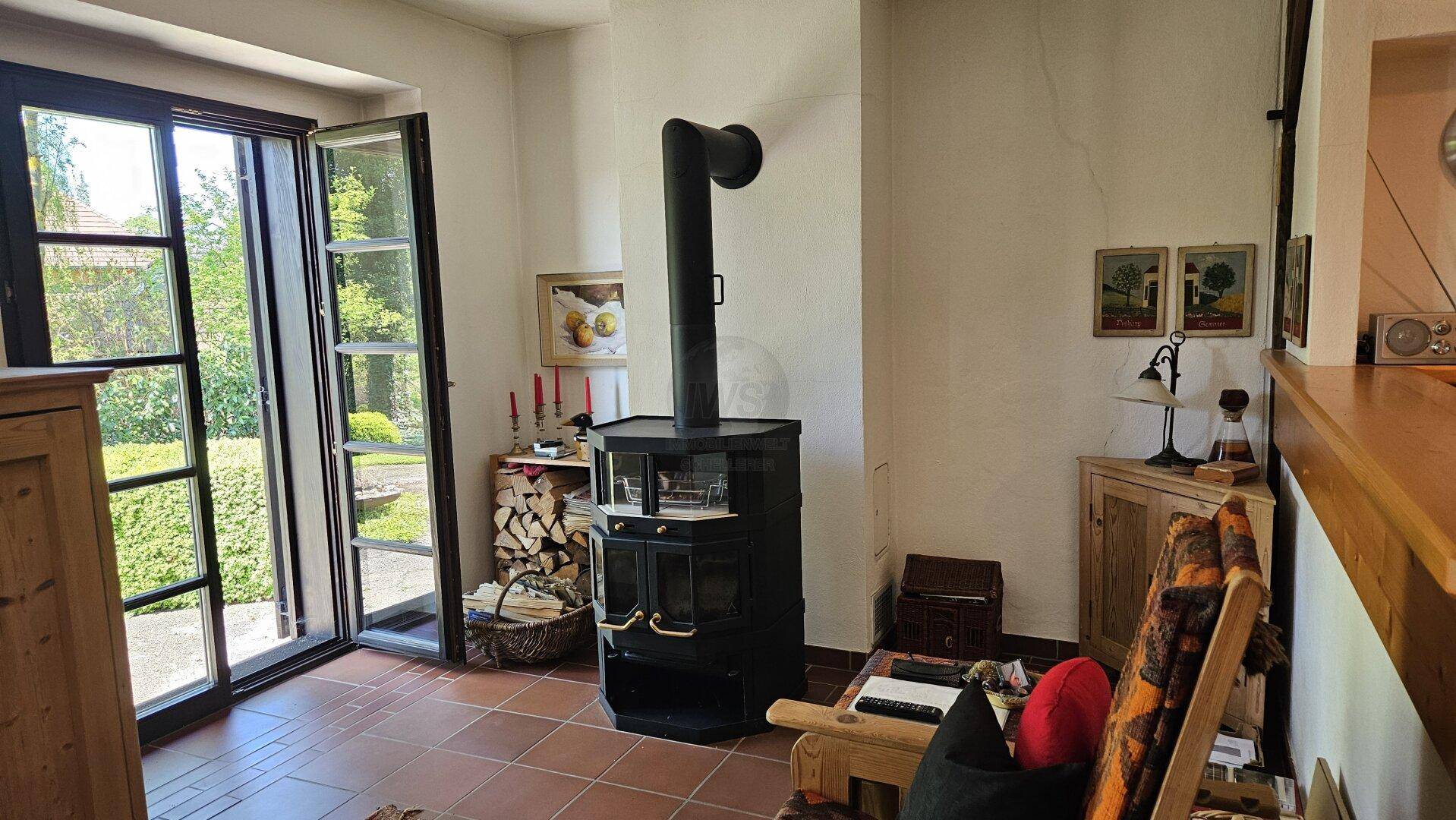 Rustikales Wohnzimmer mit Kaminofen, Terrakottaboden und direktem Zugang zum Garten.