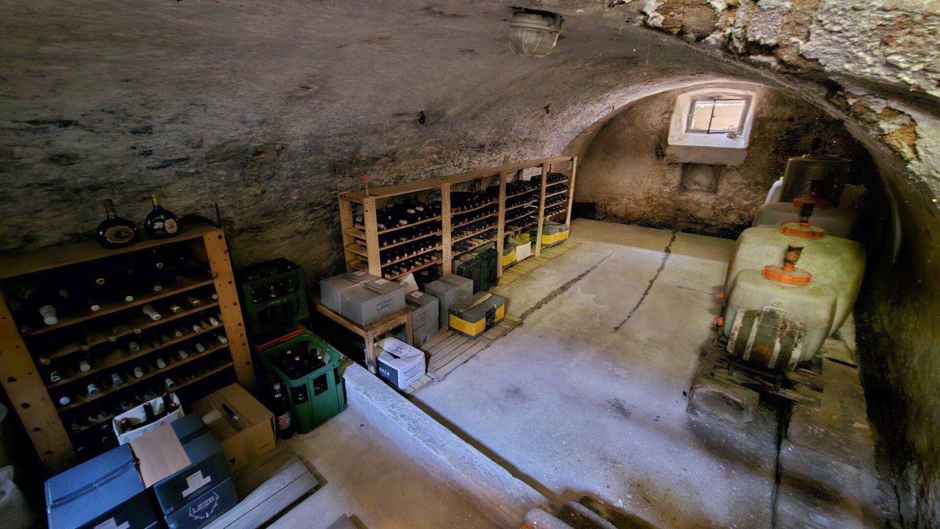 Geräumiger Weinkeller mit Steinwänden, Gewölbedecke und Regalen zur Weinlagerung.