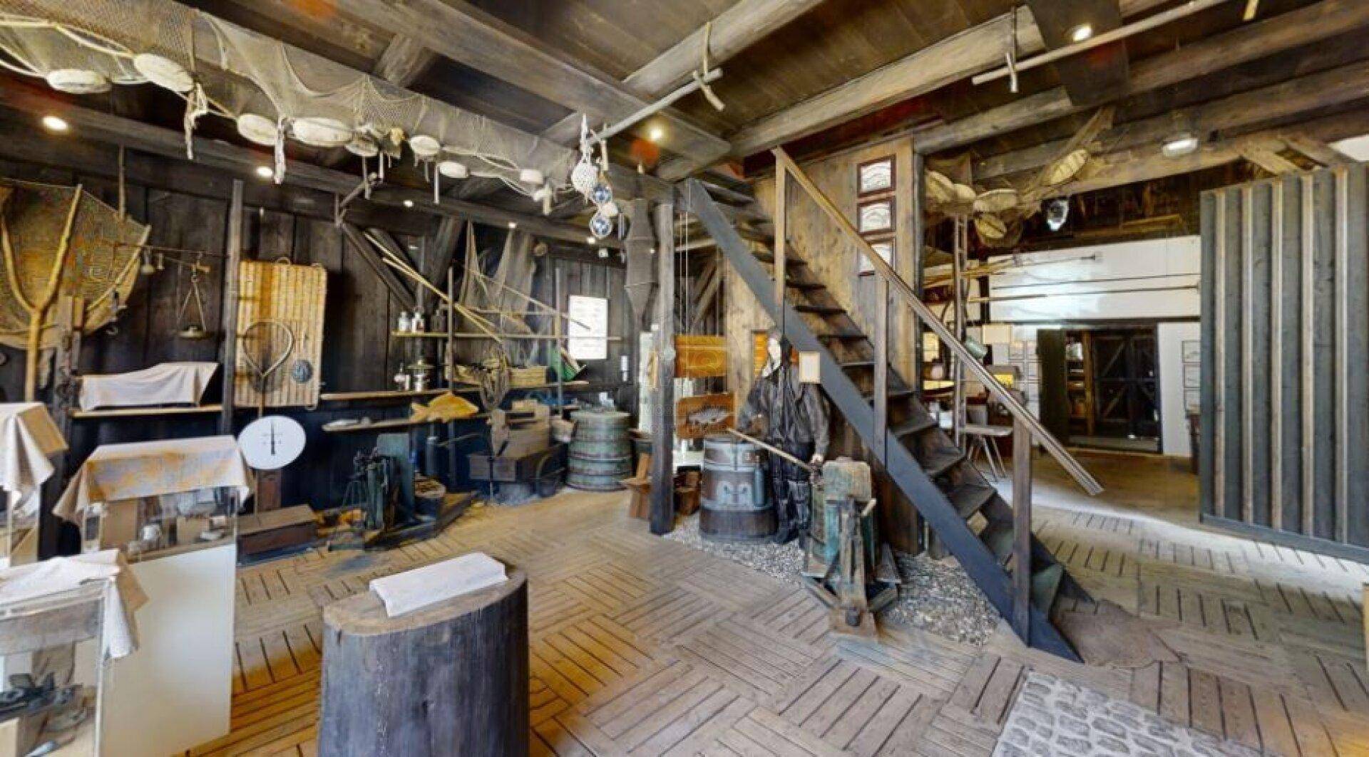 Historischer Werkstattraum mit Holzböden, sichtbaren Balken und traditionellen Geräten.