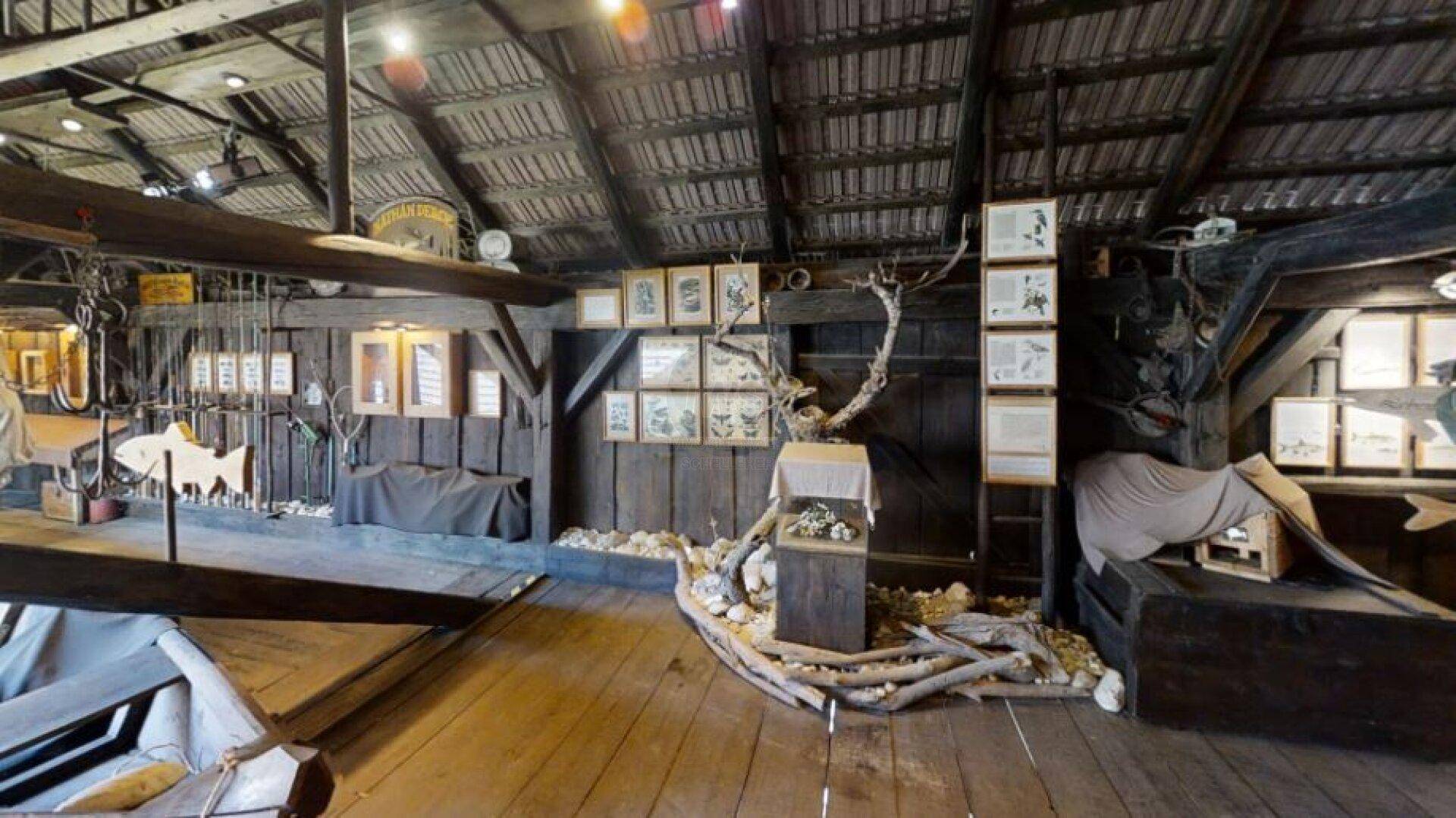 Dachbodenbereich, umgewandelt in ein Museum mit Holzwänden, Dachschrägen und Ausstellungsstücken.