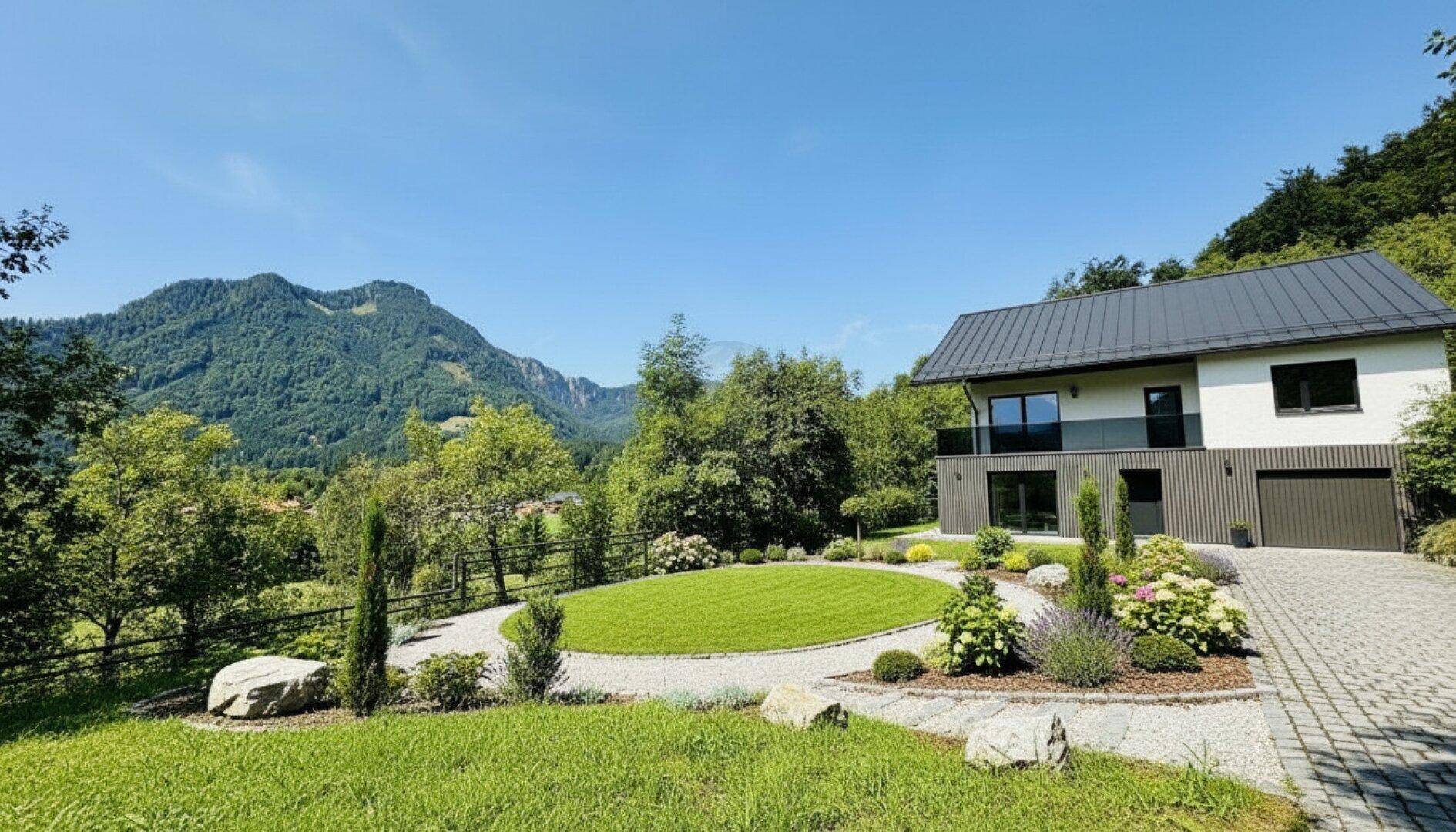 Modernes Haus mit gepflegtem Garten, Auffahrt und herrlichem Bergblick unter blauem Himmel.