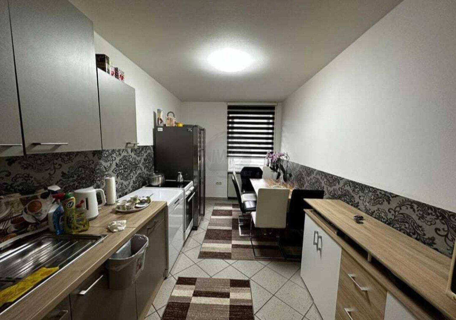 Schmale Küche mit Essbereich, Einbauschränken und Fliesenboden.