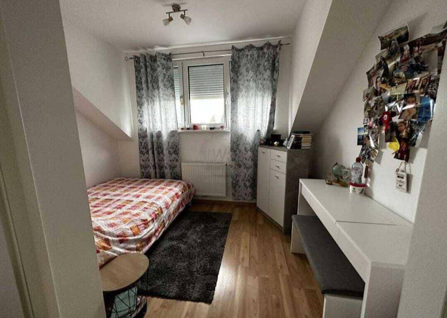 Helles Kinderzimmer im Dachgeschoss mit Holzboden, Einzelbett und Schreibtisch.