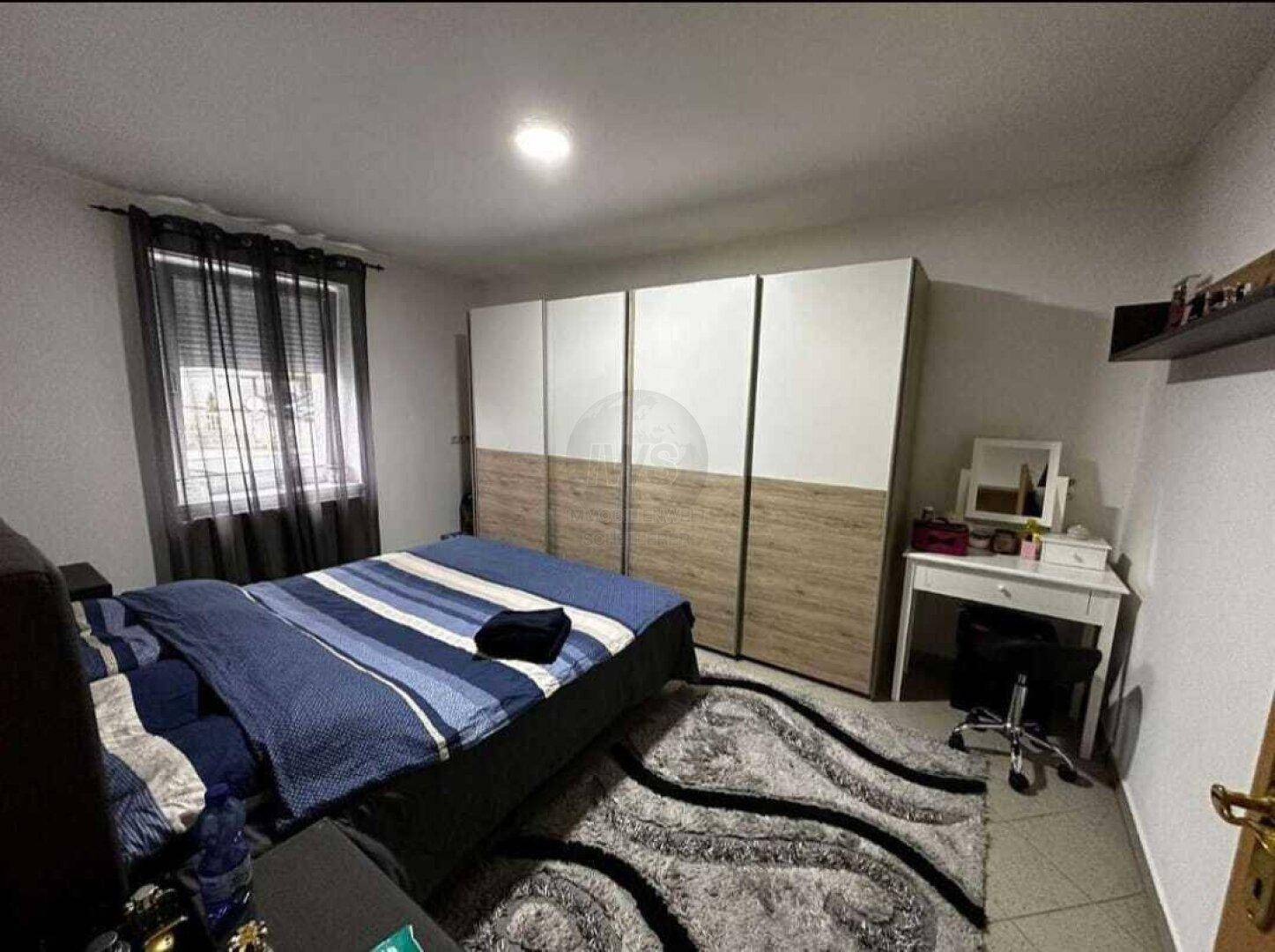 Schlafzimmer mit großem Kleiderschrank, Doppelbett und Schminktisch.
