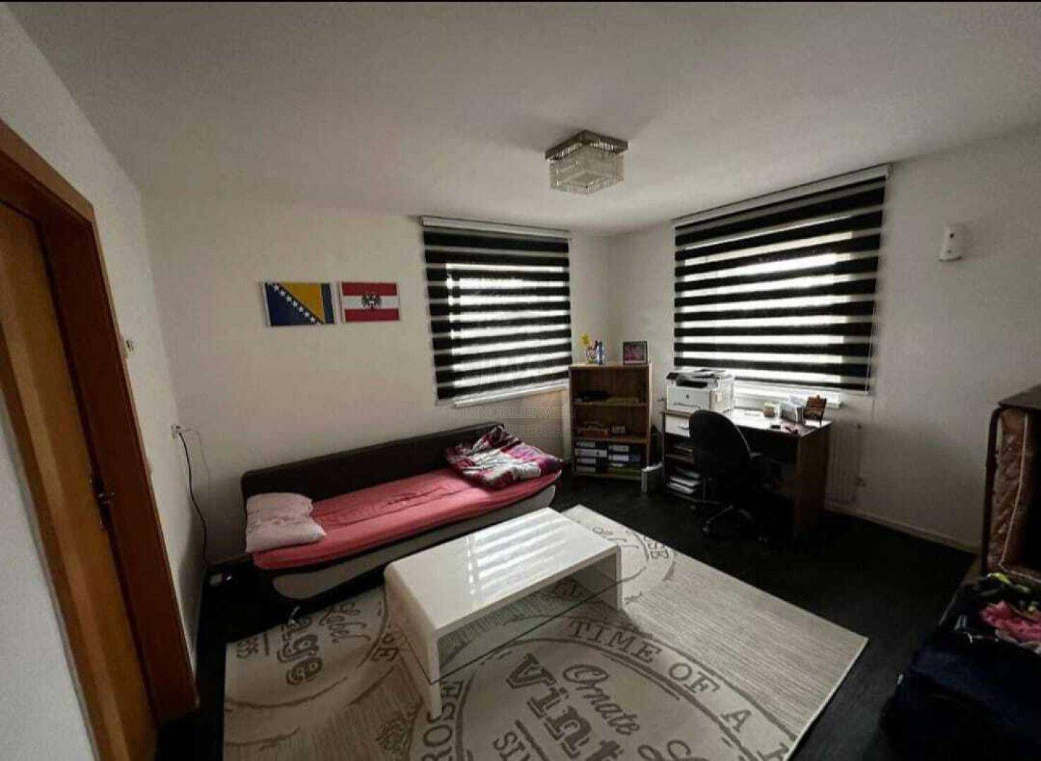 Arbeitszimmer mit Schreibtisch, Sofa und Teppichboden.