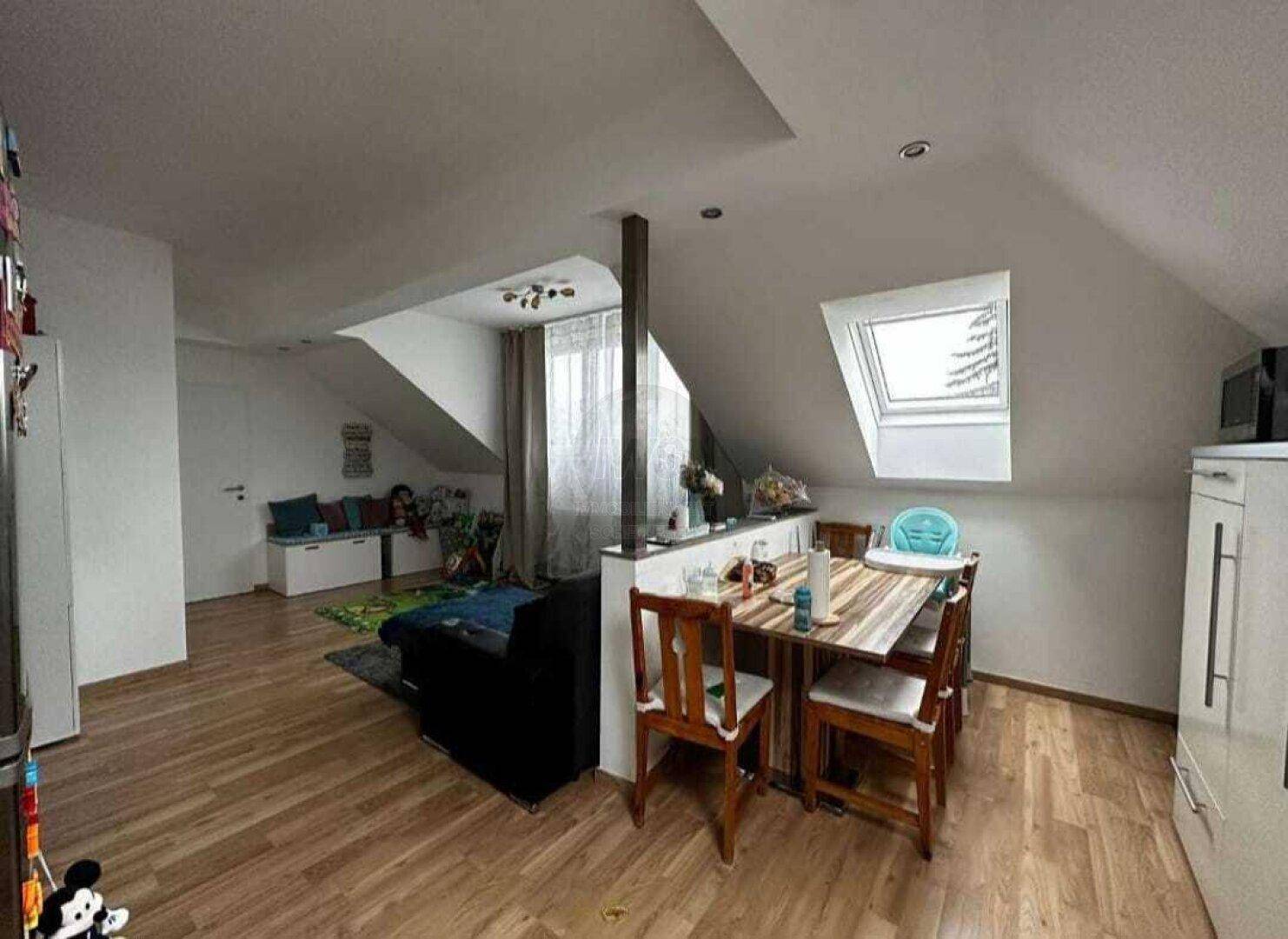 Essbereich im offenen Dachgeschoss mit Holztisch und Blick in den Wohnbereich.