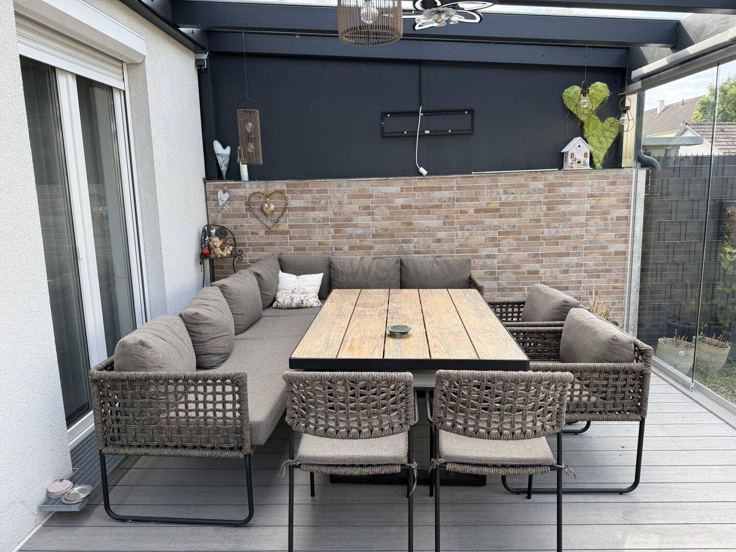 Stilvoller Essbereich auf der verglasten Terrasse mit großem Tisch und bequemen Sitzgelegenheiten.