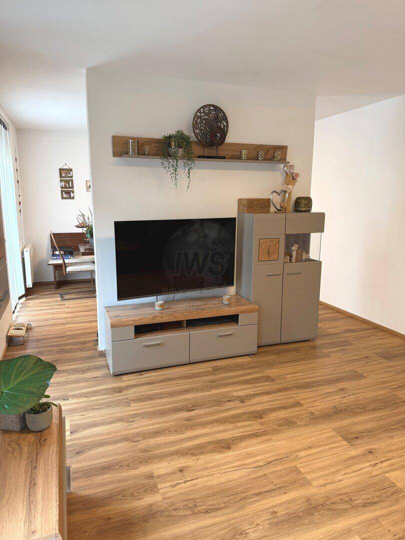 Heller Wohnbereich mit modernem TV-Möbel und durchgehendem Laminatboden.