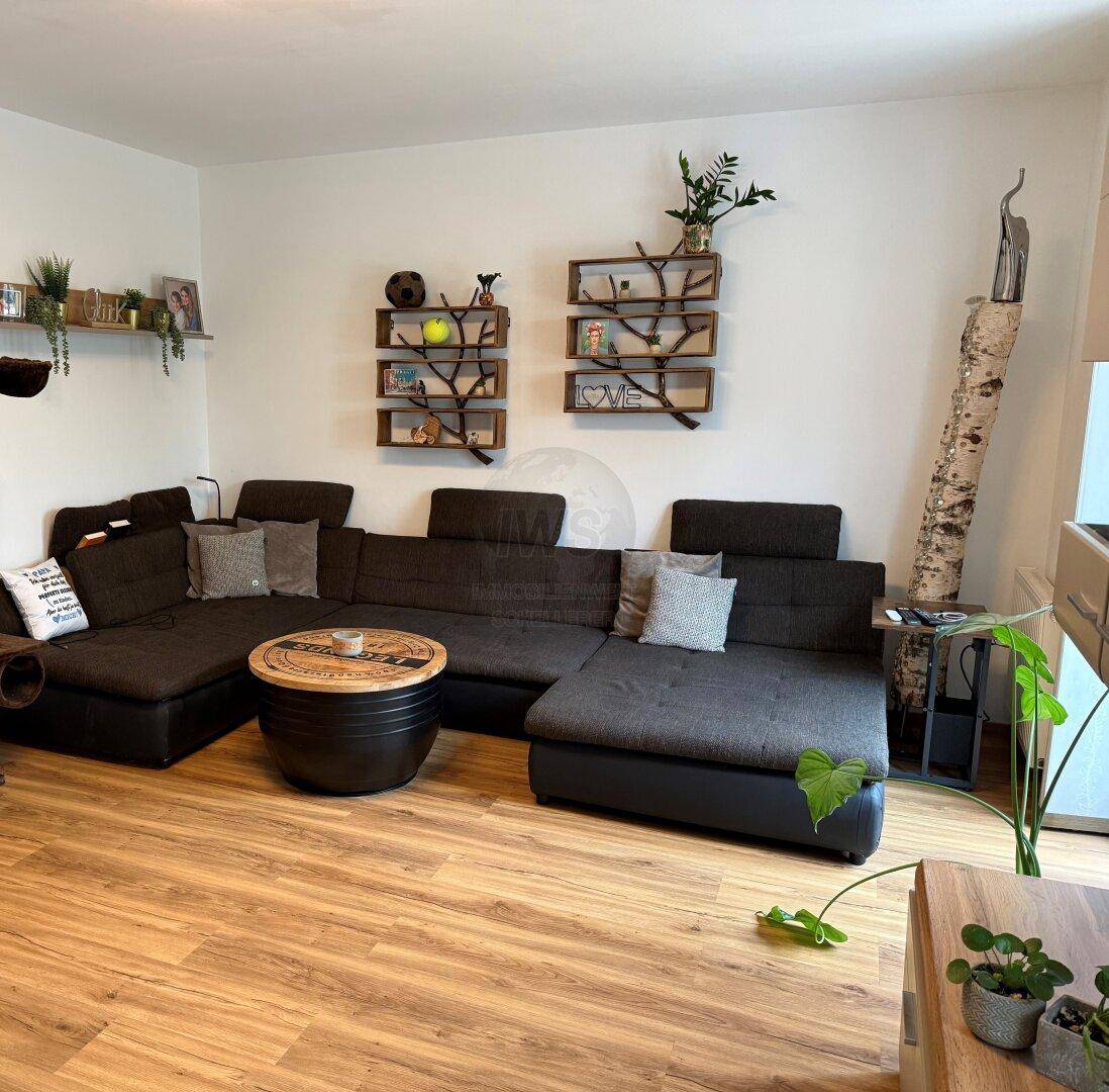 Gemütliches Wohnzimmer mit großem Ecksofa, modernen Holzregalen und Laminatboden.